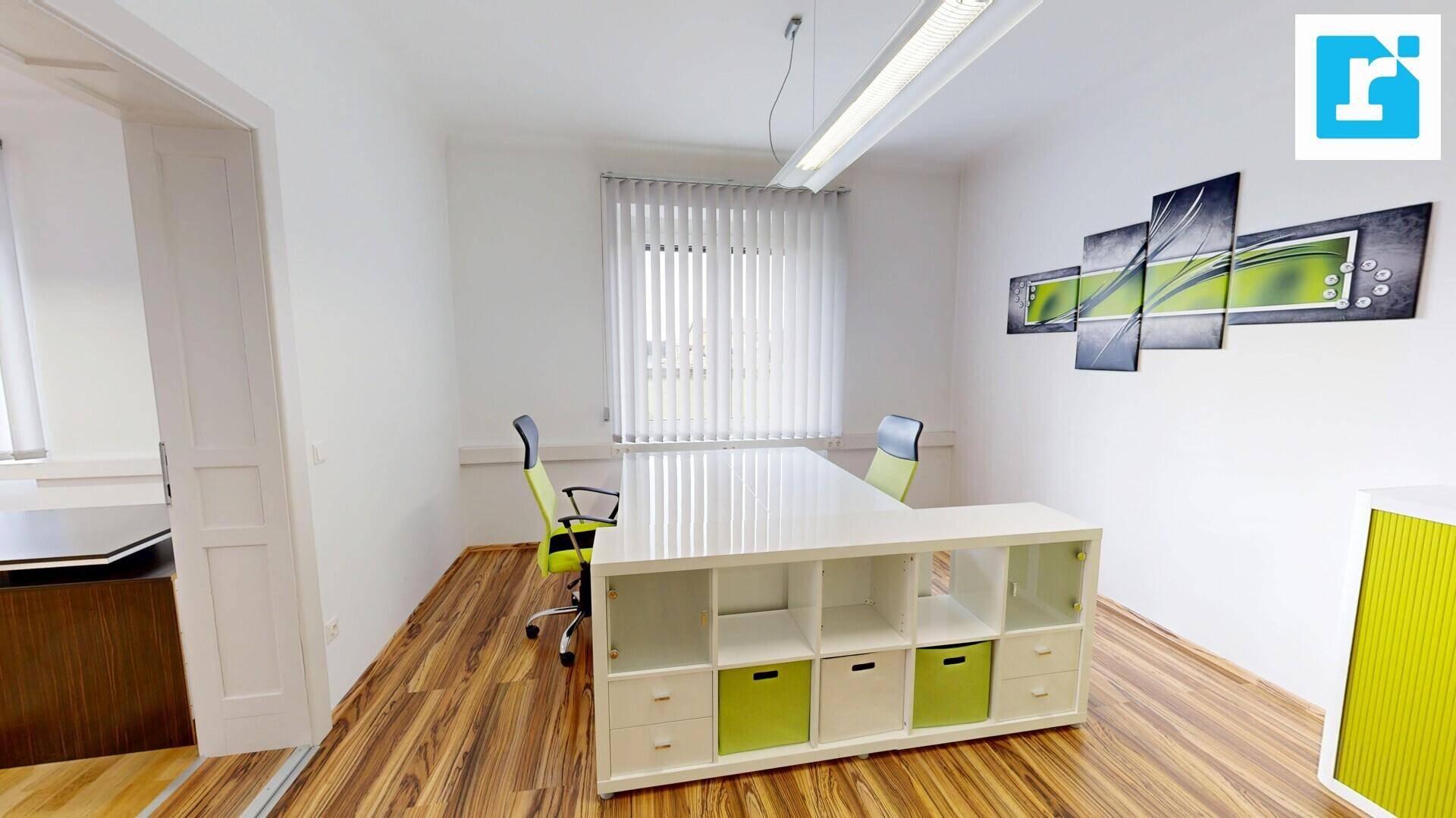 Helles Büro mit Holzboden, einem weißen Regal und modernen grünen Bürostühlen, ideal für kreatives Arbeiten.