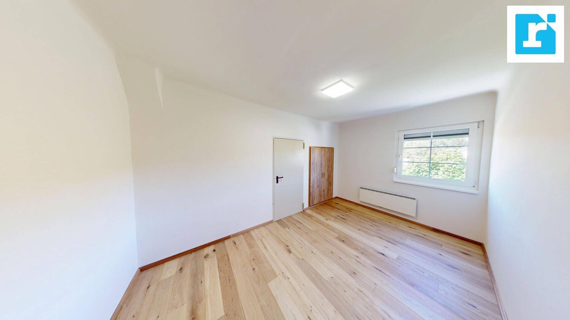 Geräumiges Schlafzimmer mit Holzdielenboden, Fenster und praktischem Einbauschrank.