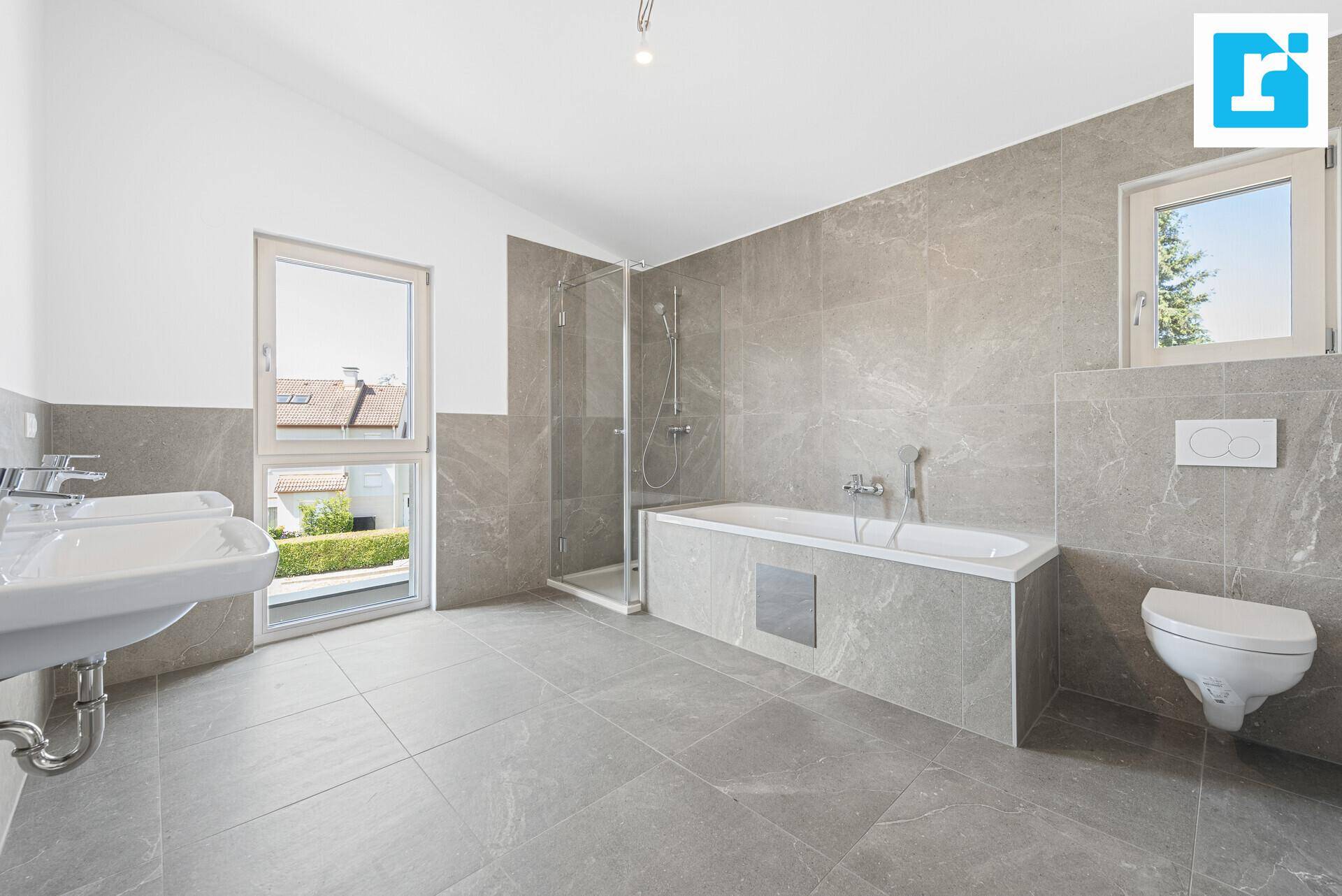 Großes, modernes Badezimmer mit Badewanne, Dusche, Doppelwaschbecken und Fenster.