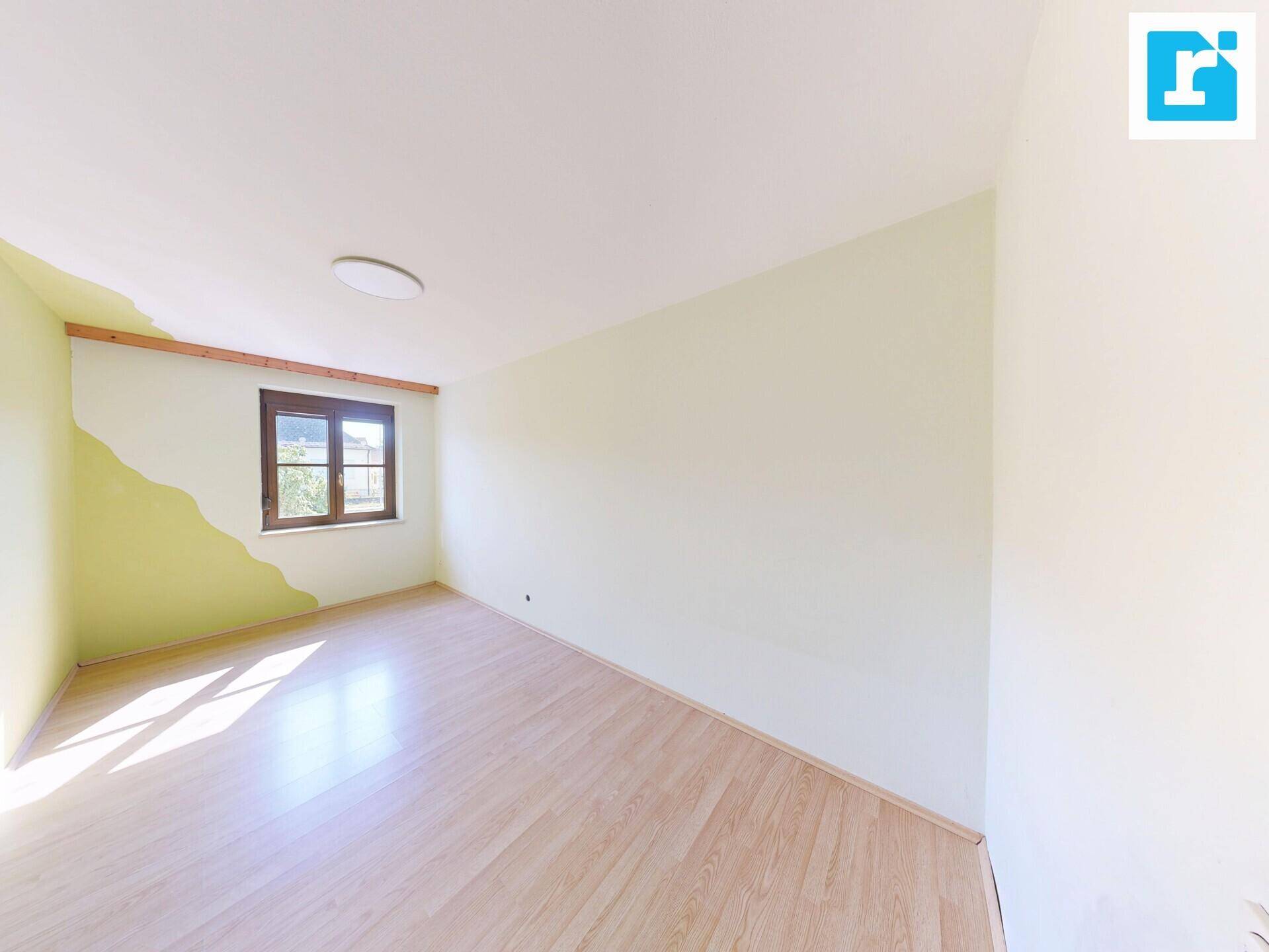 Freundliches Zimmer mit Laminatboden und einem Fenster, das den Raum mit Licht erfüllt.
