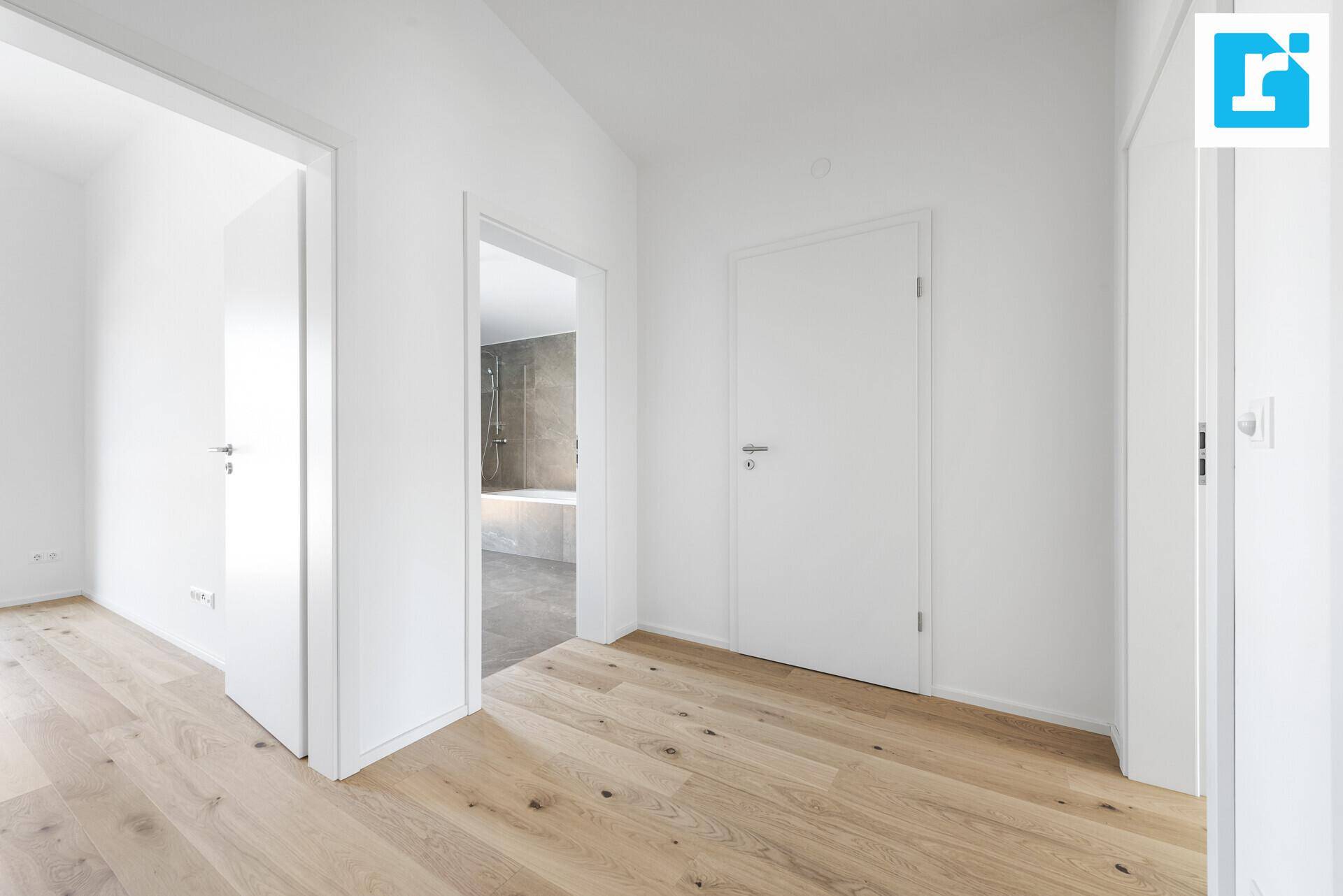 Heller Flur mit Holzboden und Zugang zu verschiedenen Zimmern, inklusive einem Badezimmer.