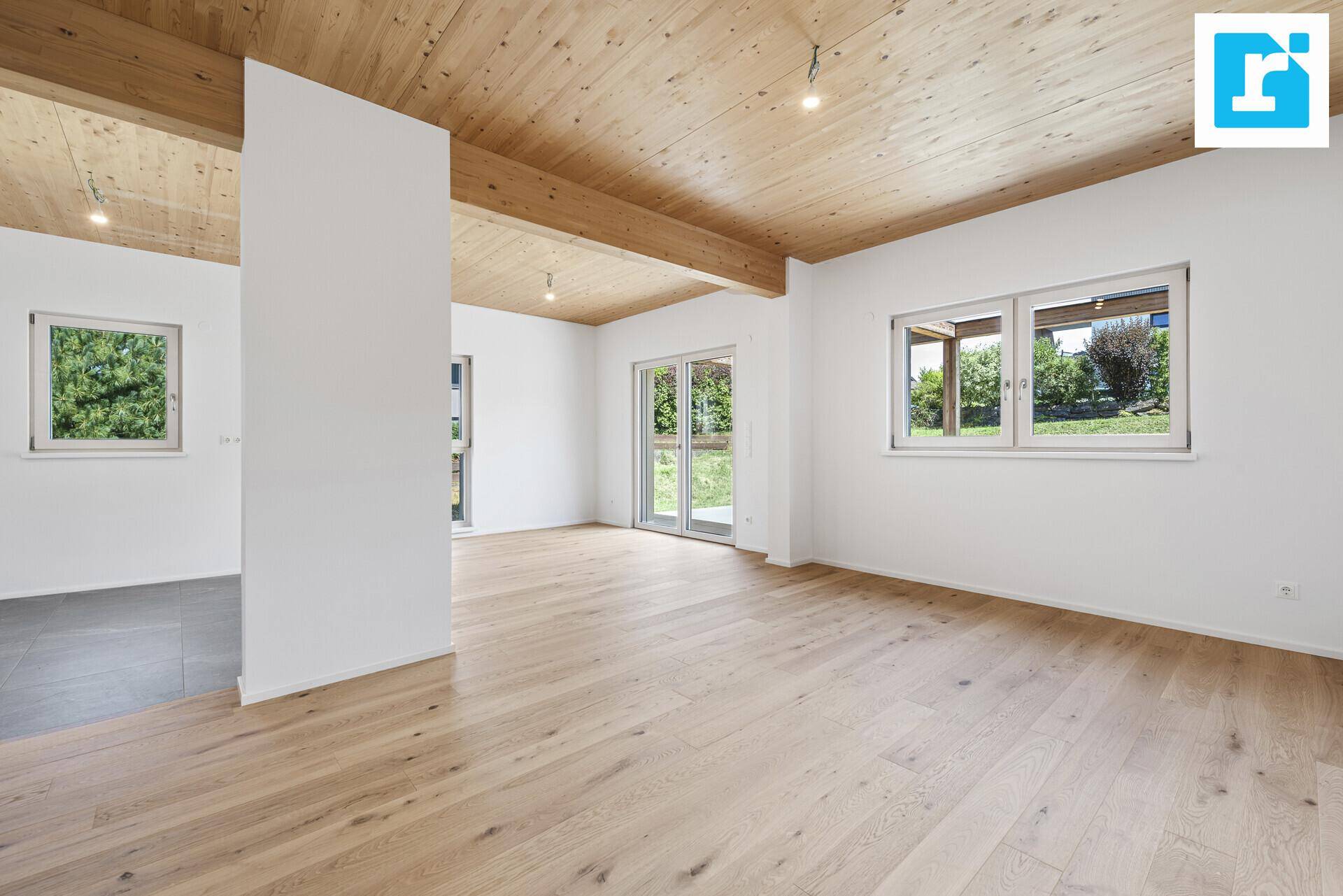 Heller Wohnbereich mit Holzbalkendecke, Parkettboden und direktem Terrassenzugang.