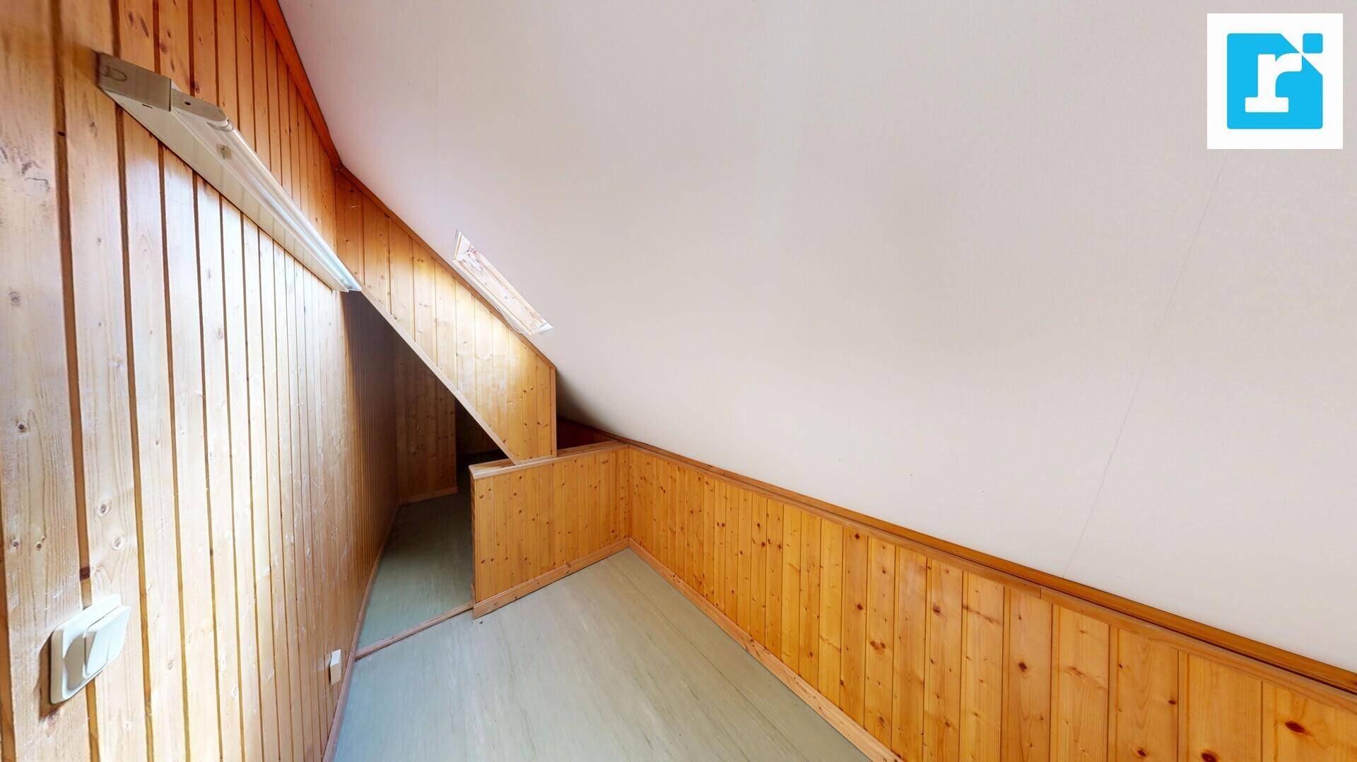 Rustikaler Dachbodenraum mit Holzverkleidung an Wänden und schräger Decke.