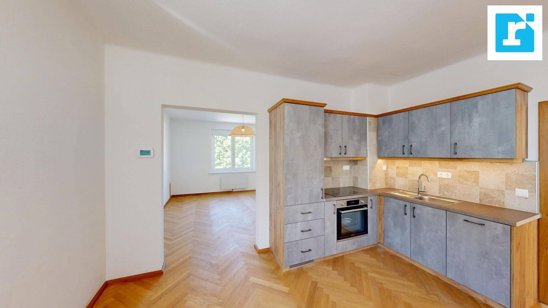 Moderne Küche mit grauen Schränken, Einbauherd und Fischgrätparkettboden.