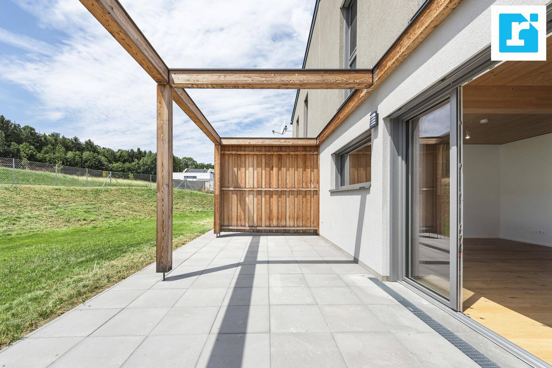 Geräumige Terrasse mit Holzpergola und direktem Zugang zum Innenbereich.