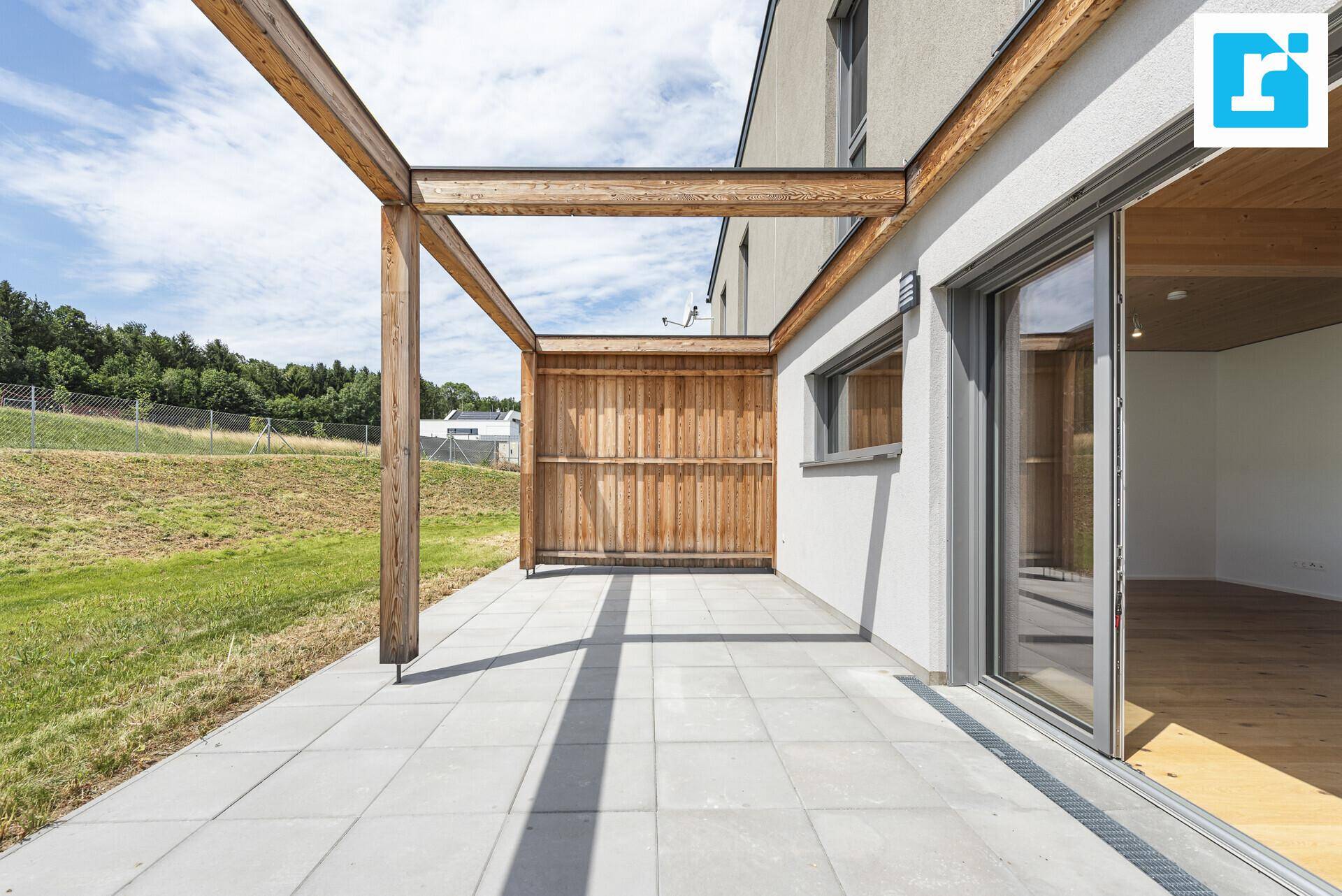 Geräumige Terrasse mit Holzpergola und direktem Zugang zum Innenbereich.