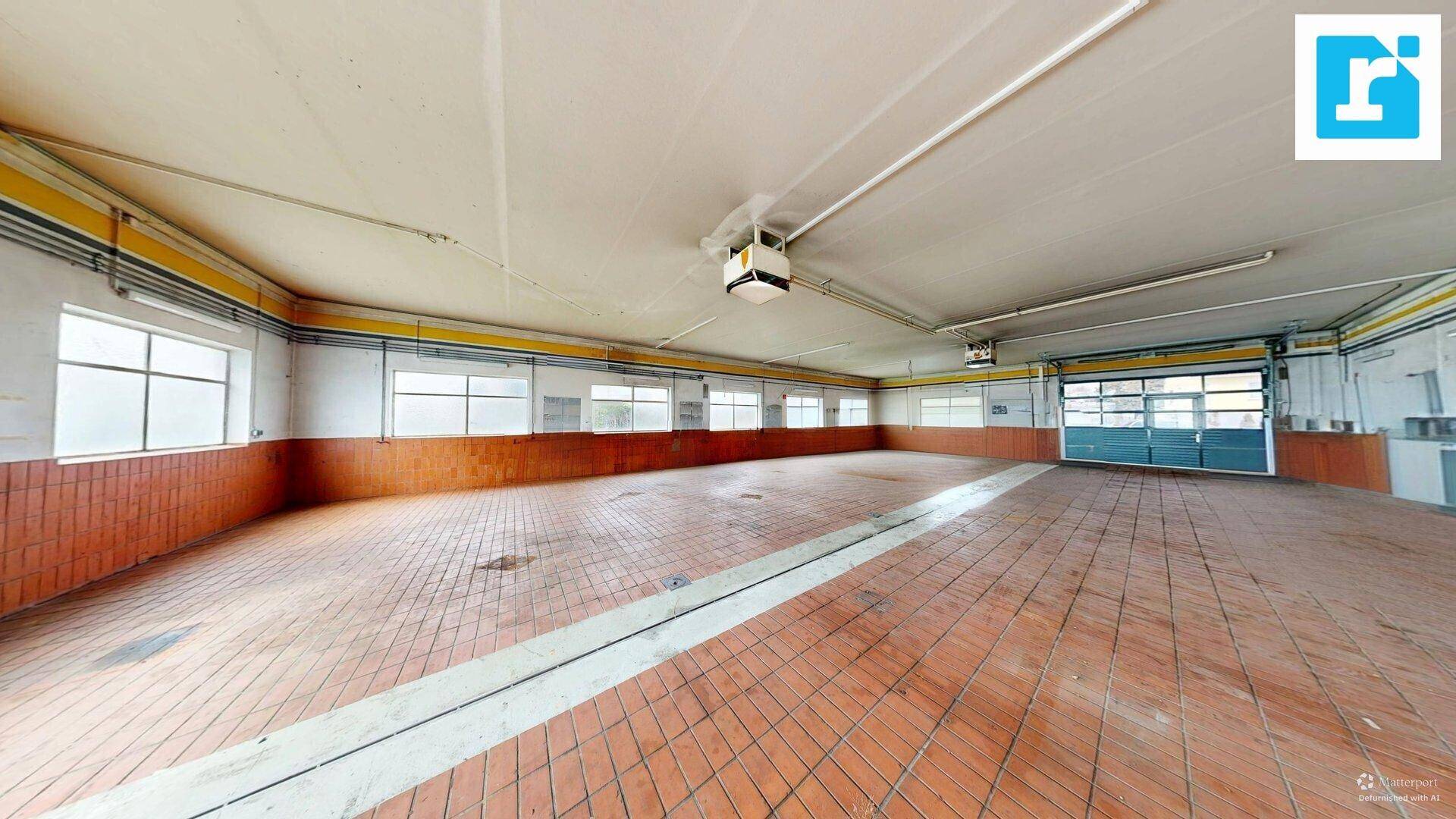 Helle Werkstatt mit Terrakotta-Fliesenboden und großen Fenstern, bietet viel Arbeitsfläche.