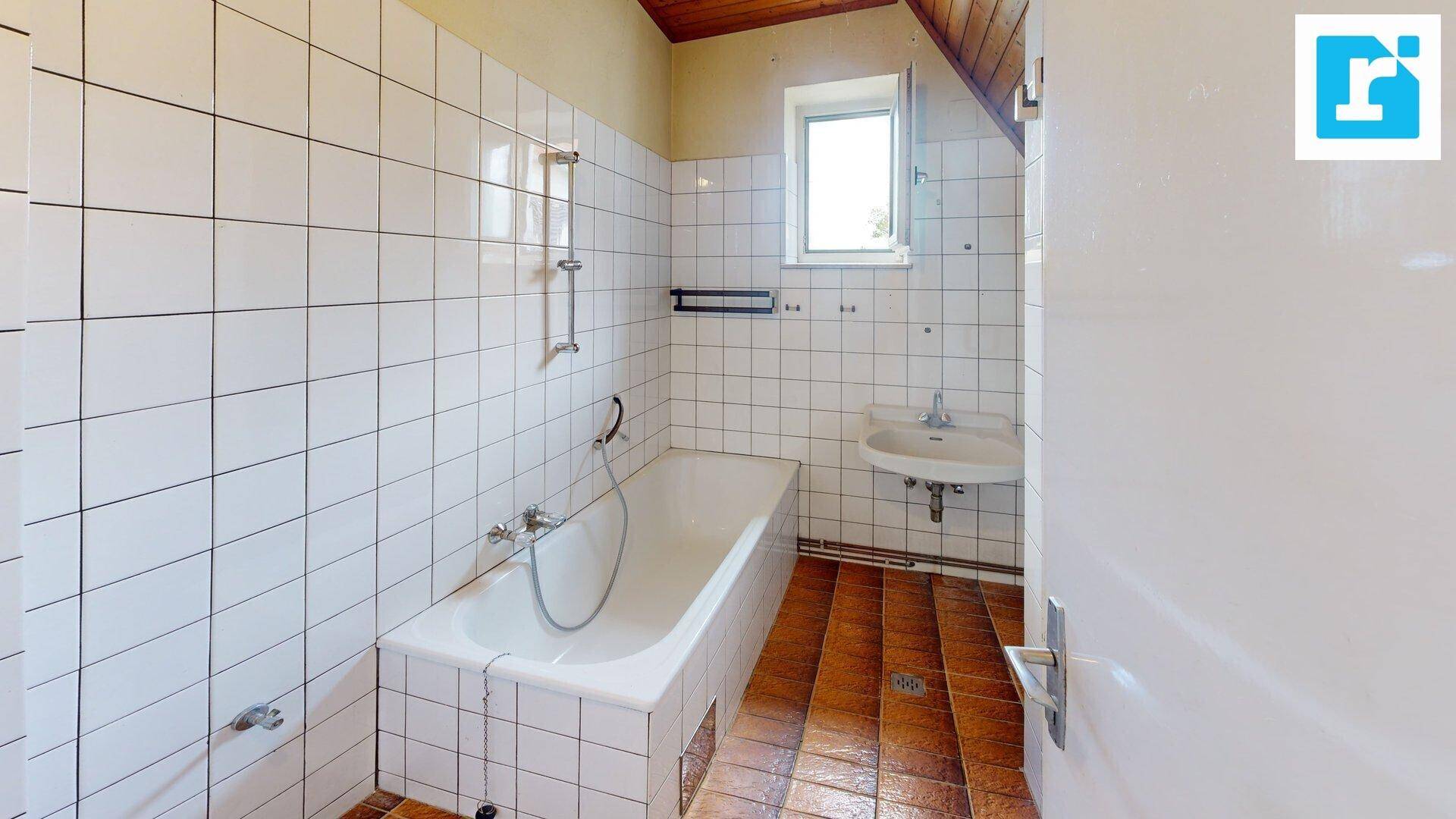 Badezimmer mit weißen Fliesen, Badewanne und Waschbecken, bereit für Modernisierung.