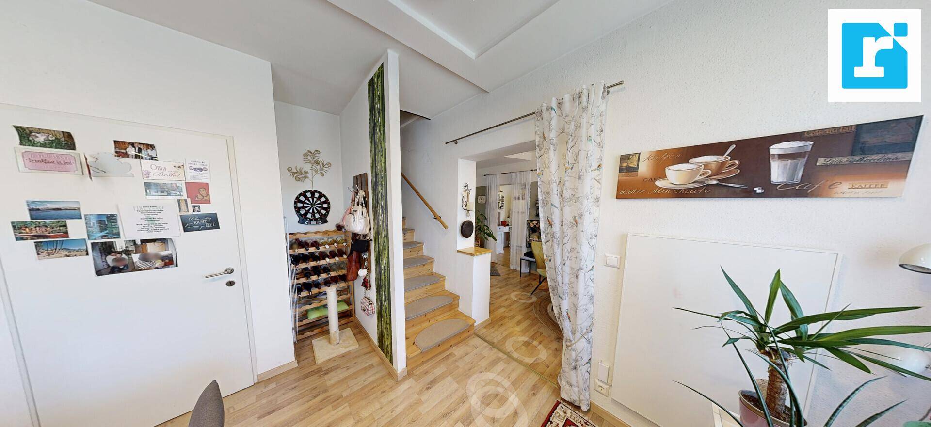 Heller Flur mit Holztreppe und Laminatboden, der zu den oberen Etagen führt.