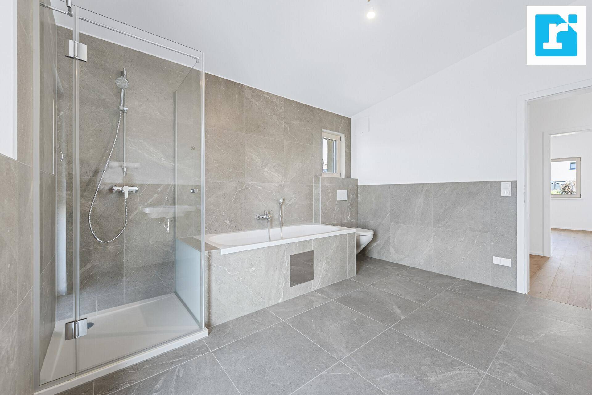 Zeitgemäßes Badezimmer mit Badewanne, Duschkabine und WC, ausgestattet mit eleganten grauen Fliesen.