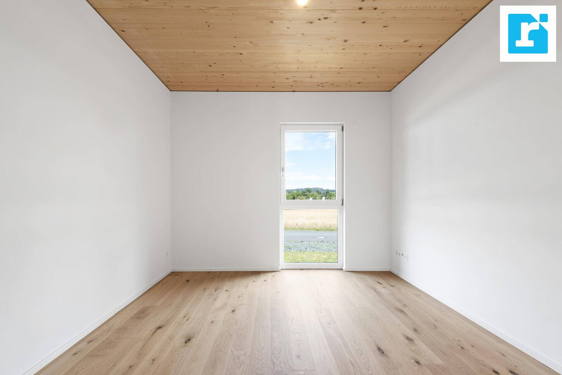 Helles Schlafzimmer mit Holzbalkendecke, Parkettboden und weitem Ausblick.