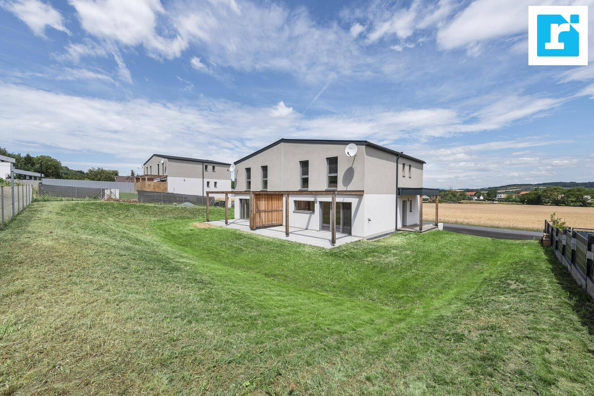 Neubau-Doppelhaushälfte mit großem Garten und Blick auf die umliegende Landschaft.