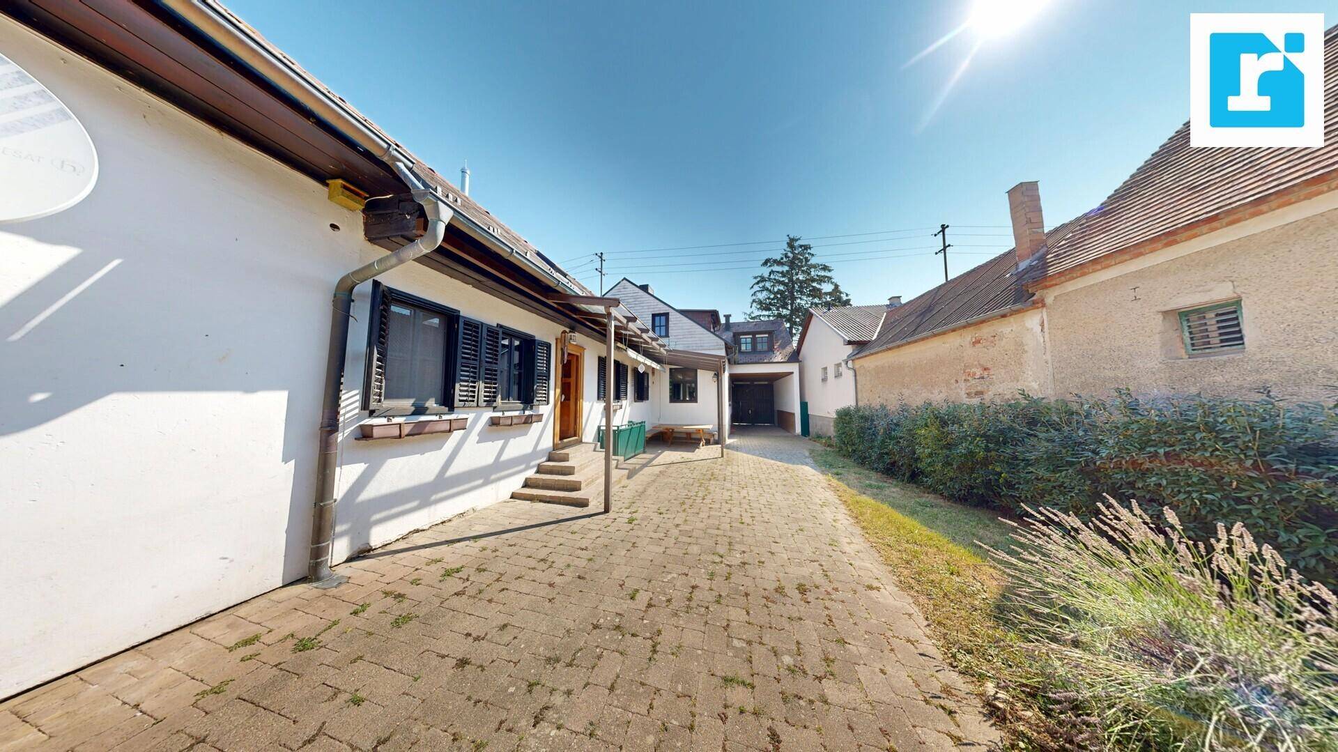 Außenansicht des Hauses mit gepflasterter Auffahrt und grüner Umgebung an einem sonnigen Tag.