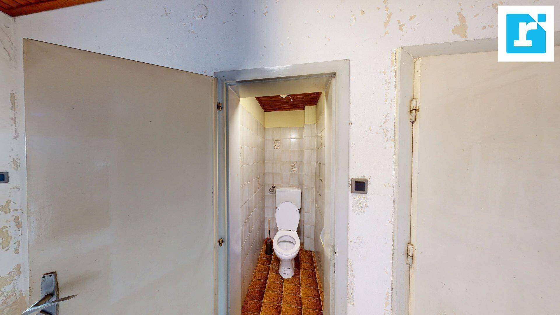 Separate Toilette mit Fliesenboden und einfacher Ausstattung, benötigt Renovierung.