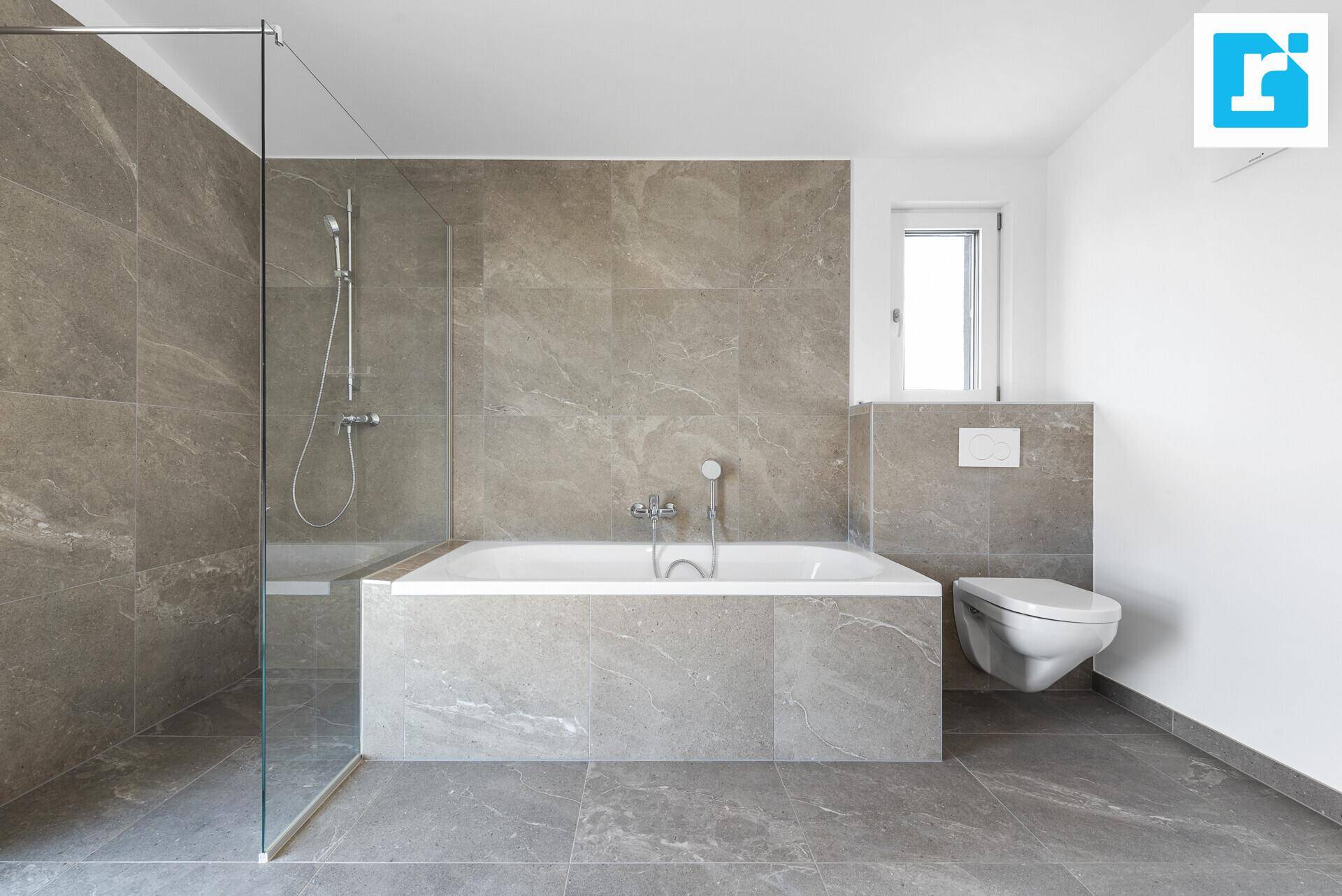 Stilvolles Badezimmer mit Badewanne, Dusche und wandhängendem WC, ergänzt durch ein kleines Fenster.