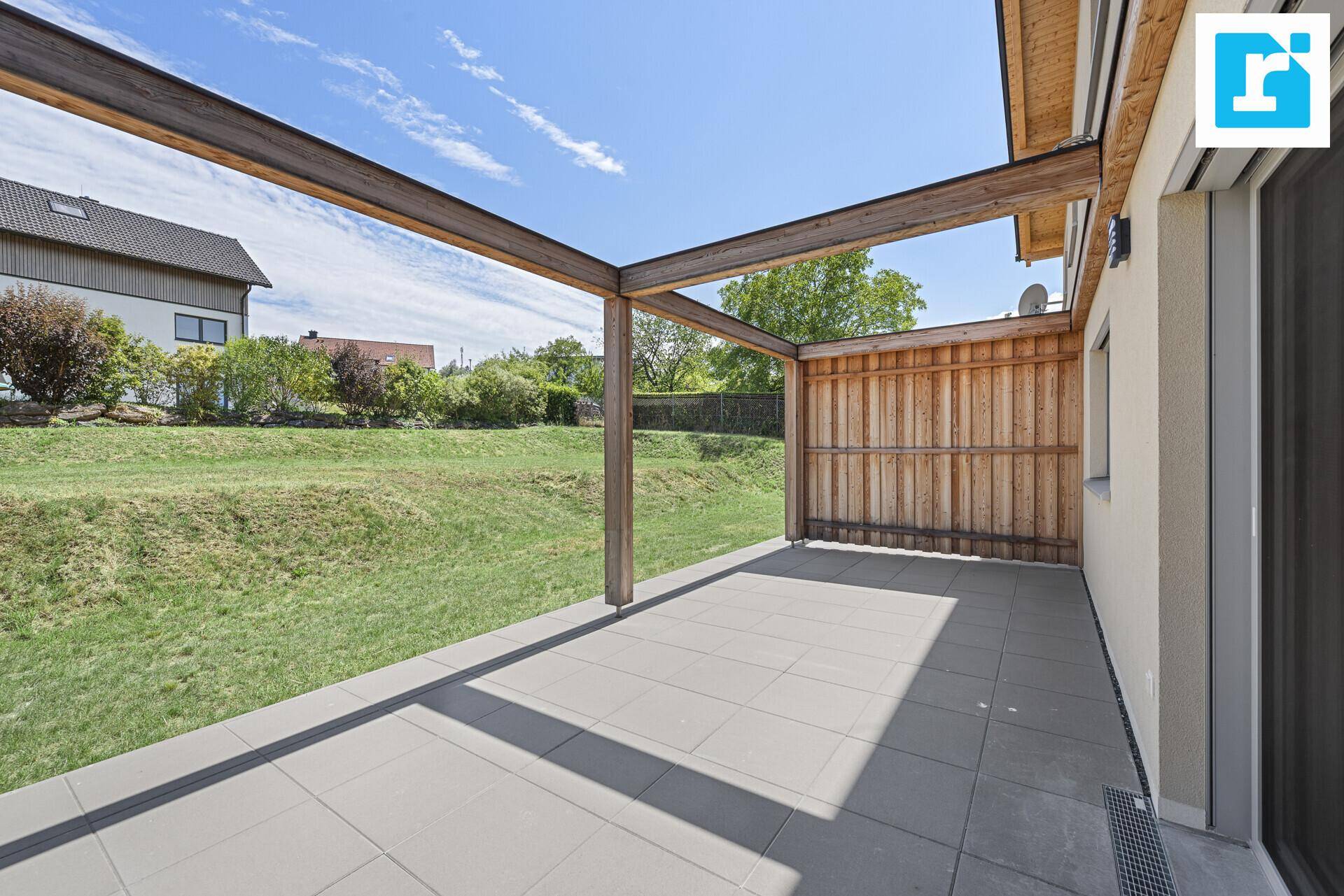 Geräumige Terrasse mit Pergola und Blick auf den grünen Gartenbereich.