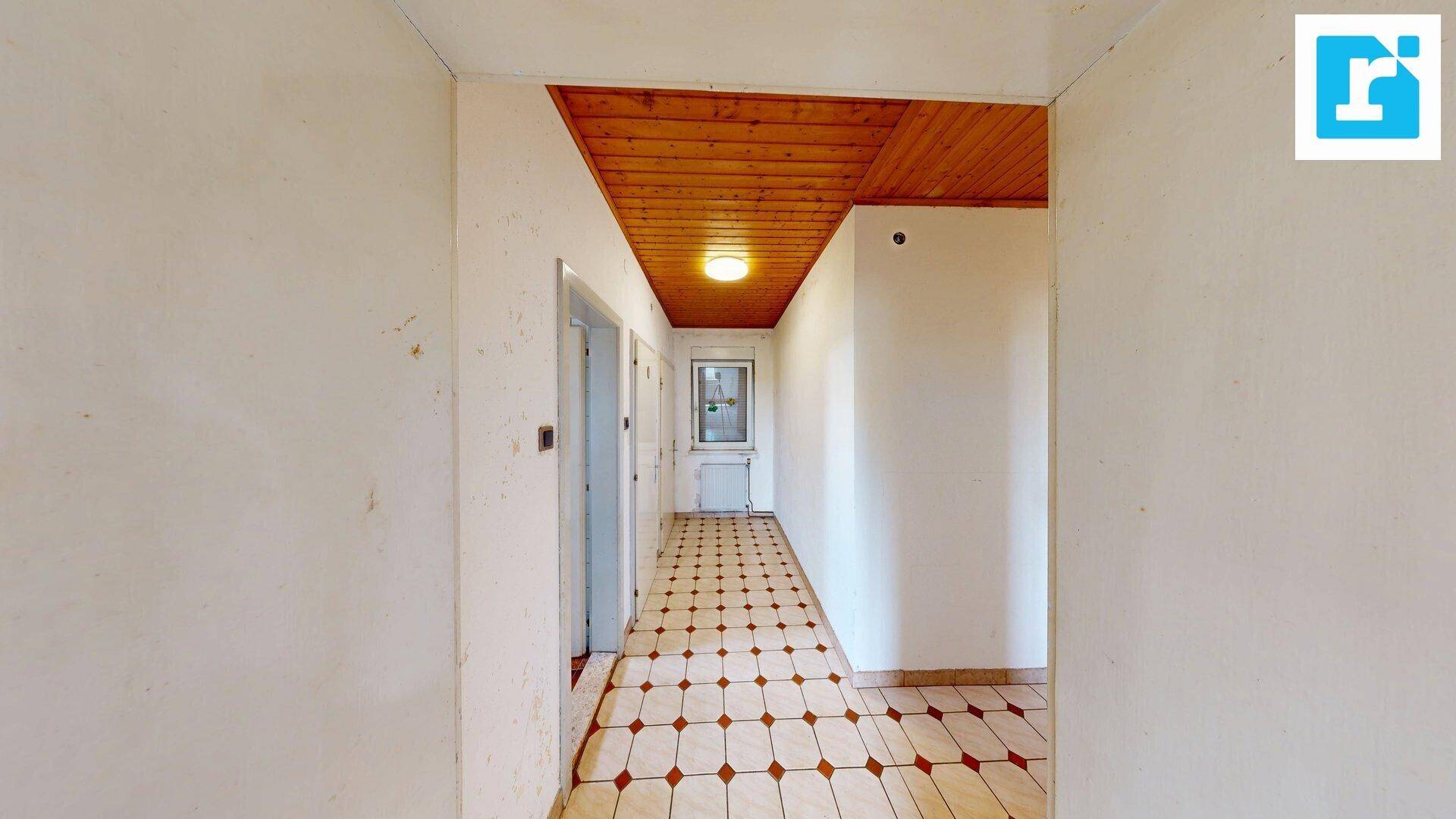 Flur mit gemusterten Fliesen und Holzdecke, führt zu verschiedenen Zimmern.
