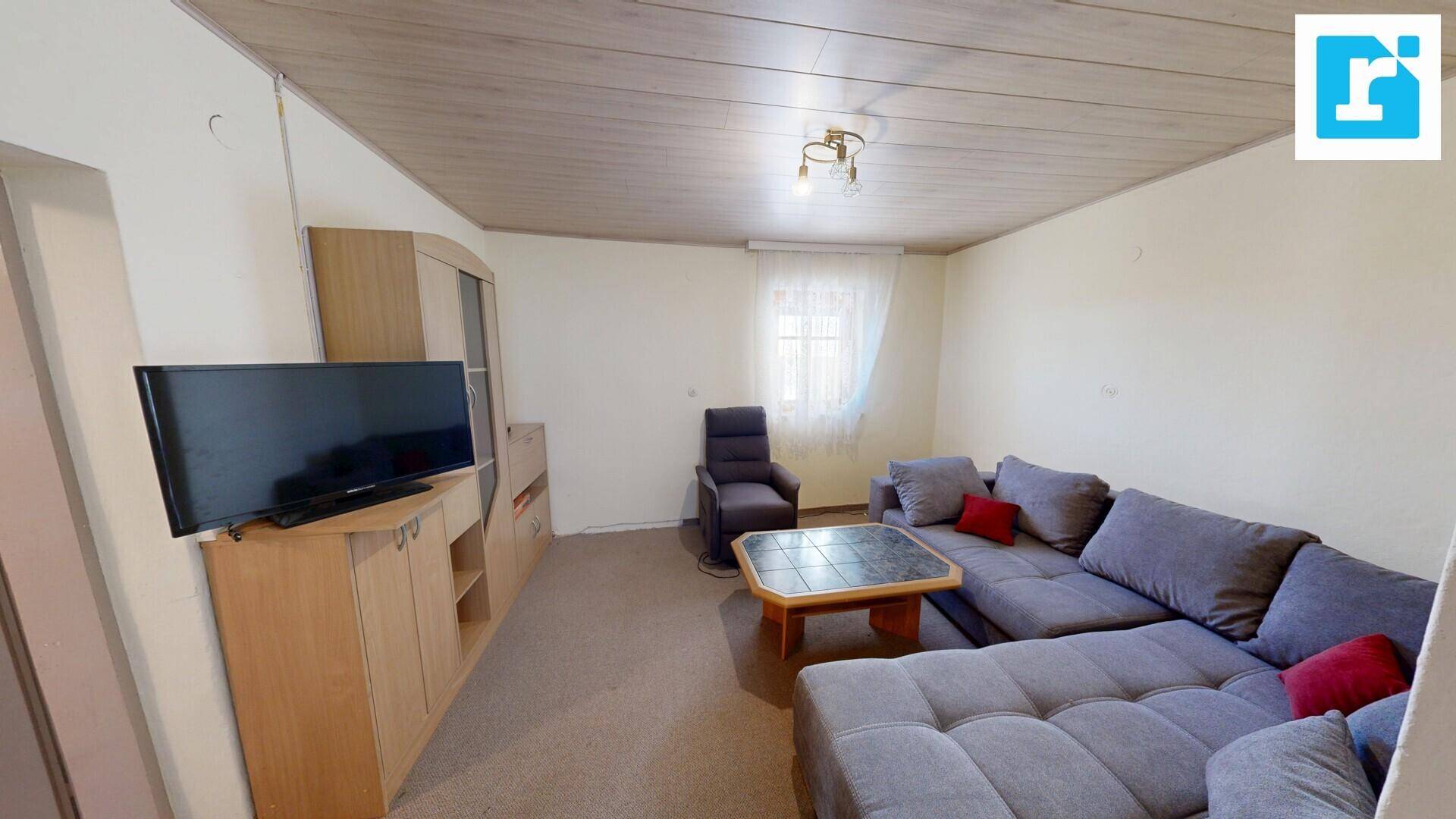 Gemütliches Wohnzimmer mit großem Sofa, TV-Möbeln und Teppichboden.