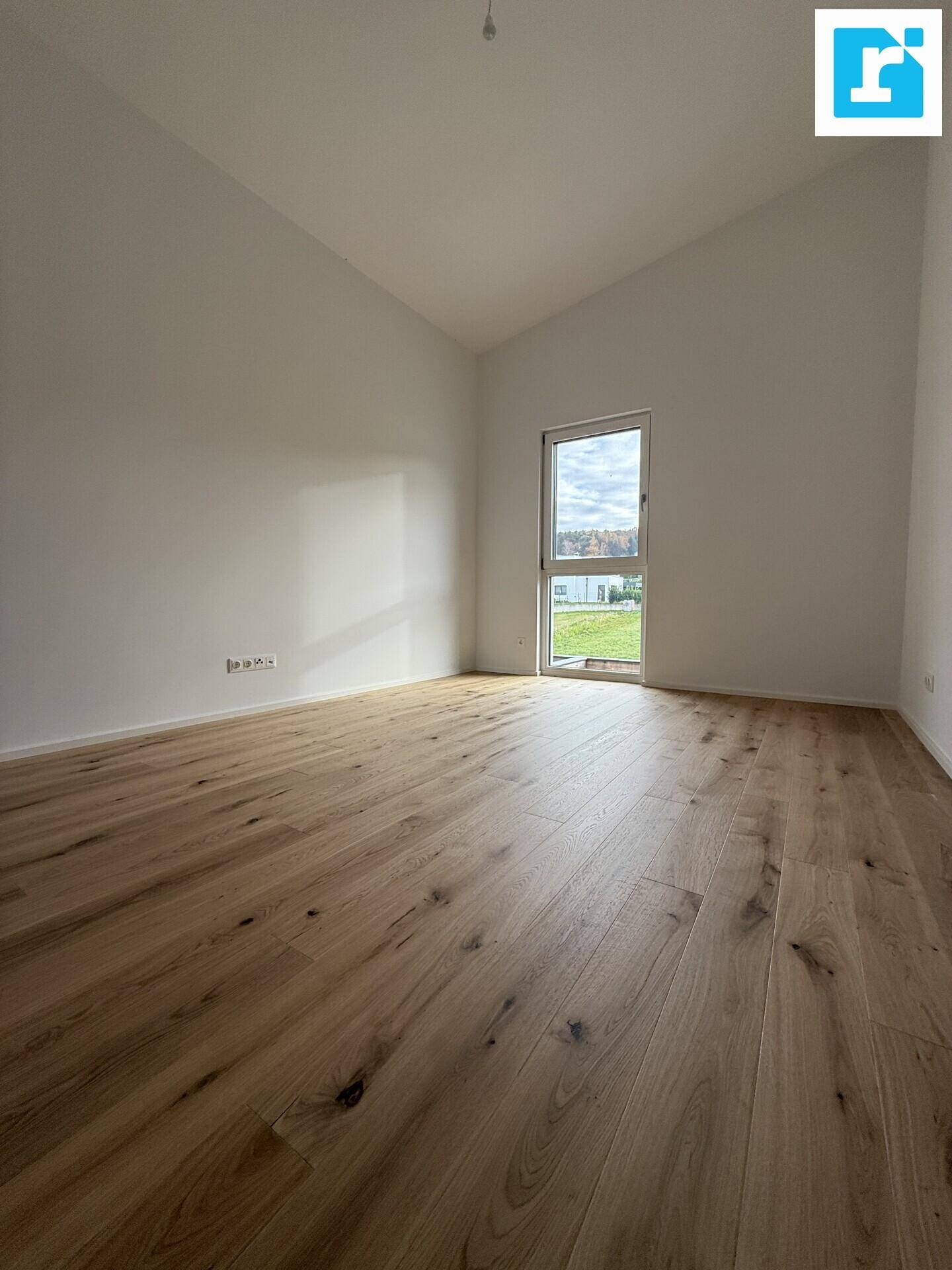 Geräumiges Schlafzimmer mit Parkettboden, hohen Decken und Fenster.