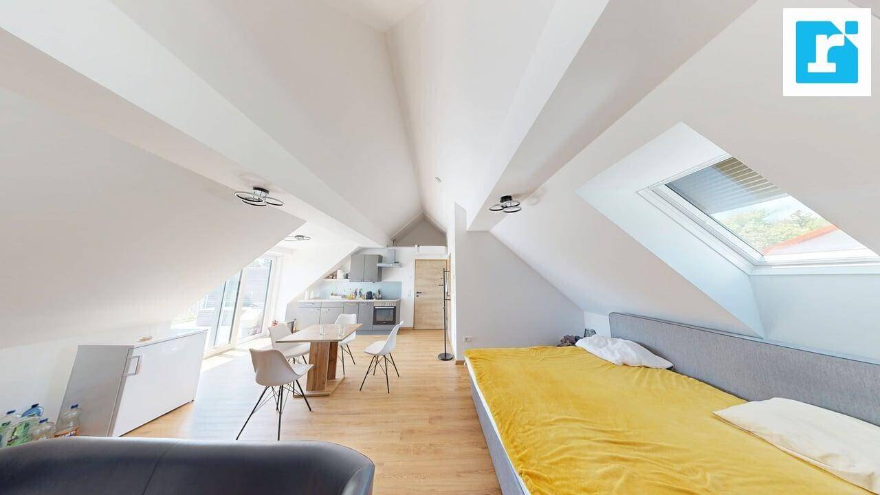 Dachgeschosswohnung mit Schlafbereich, Dachfenster und offenem Übergang zur Küche und zum Essbereich.