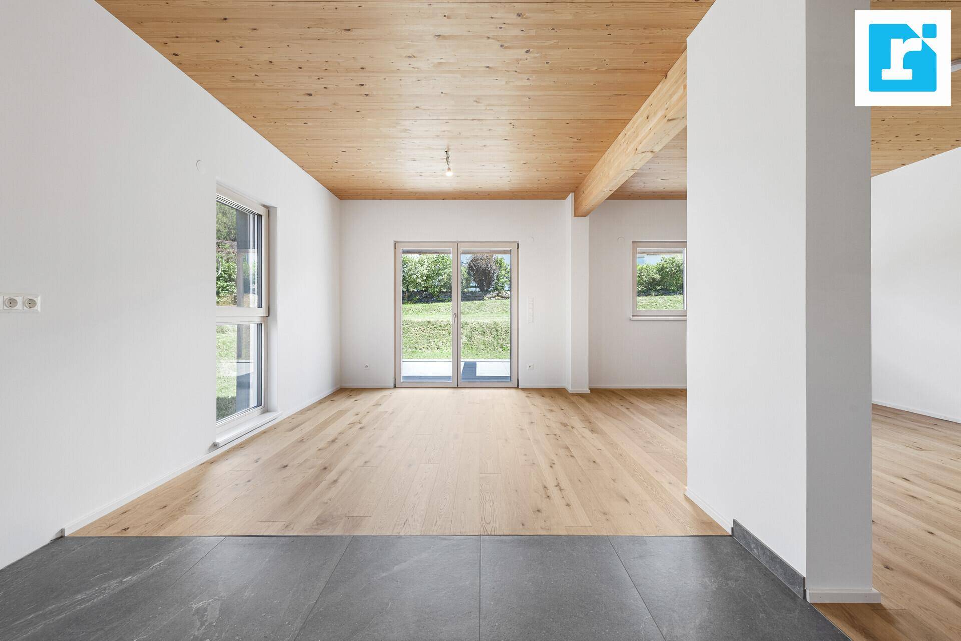 Geräumiger Wohnbereich mit Holzbalkendecke, Parkettboden und direktem Zugang zum Garten.