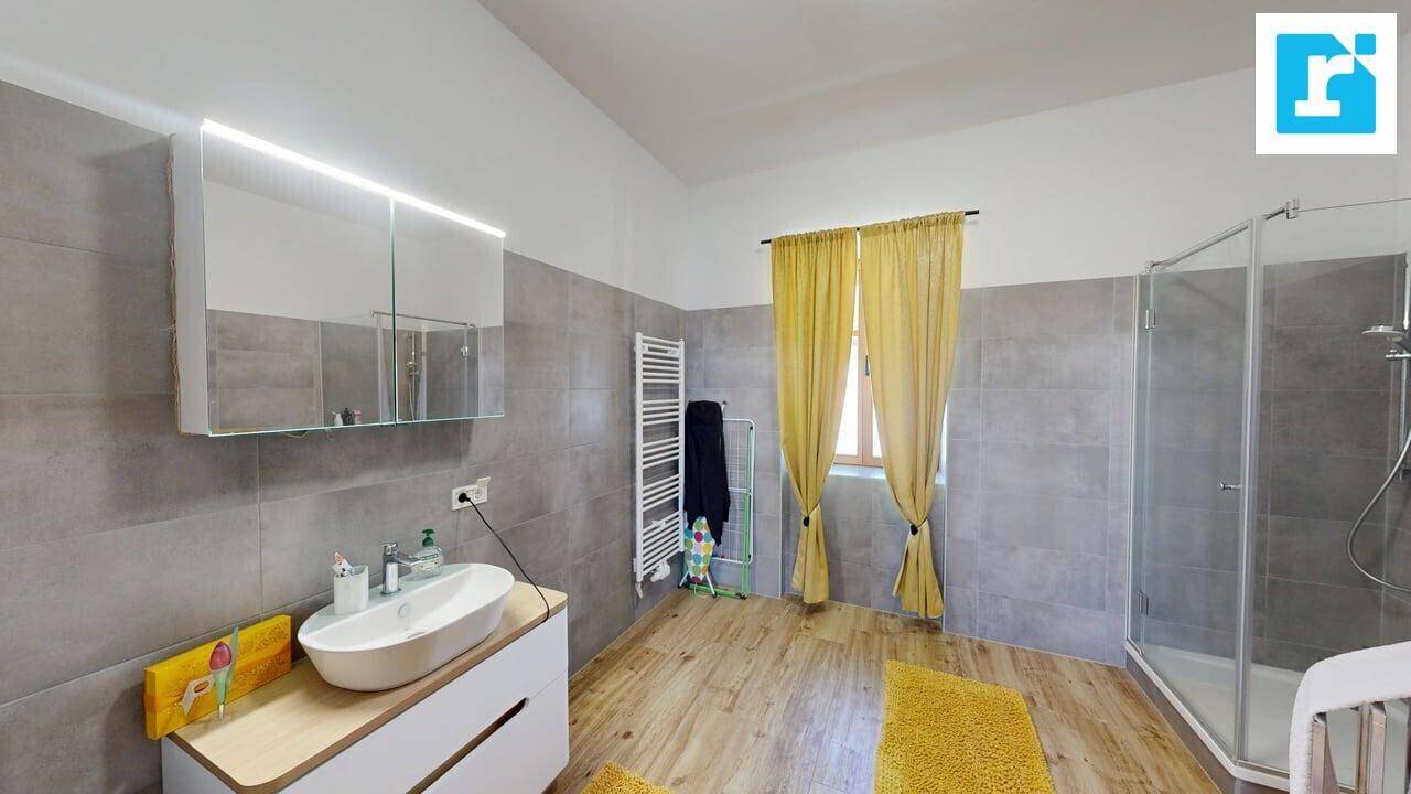 Helles Badezimmer mit modernem Waschtisch, Spiegelschrank, Handtuchheizkörper und Duschkabine.