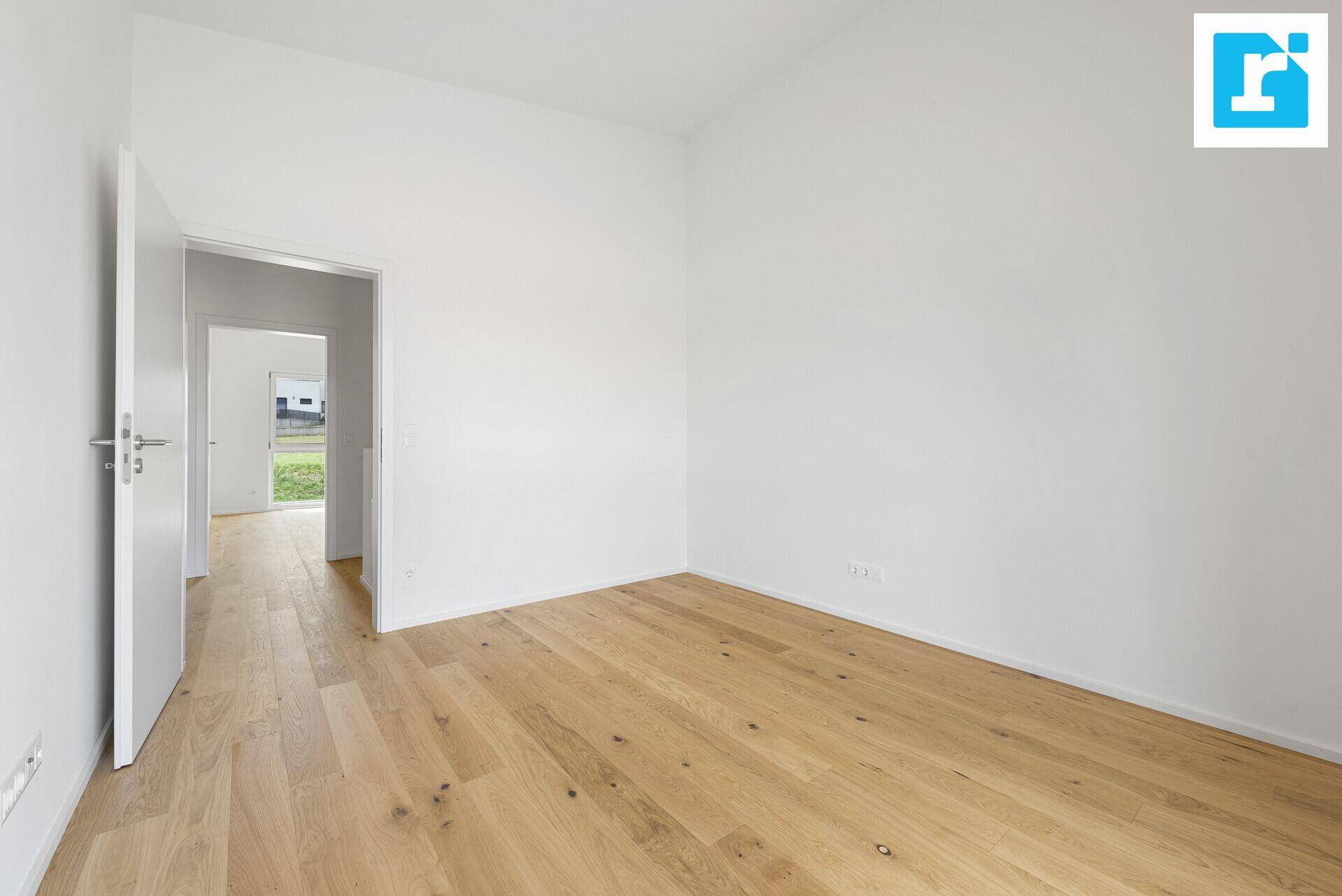 Geräumiges Zimmer mit hellem Holzboden und weiß gestrichenen Wänden, ideal für Schlaf- oder Arbeitsbereich.