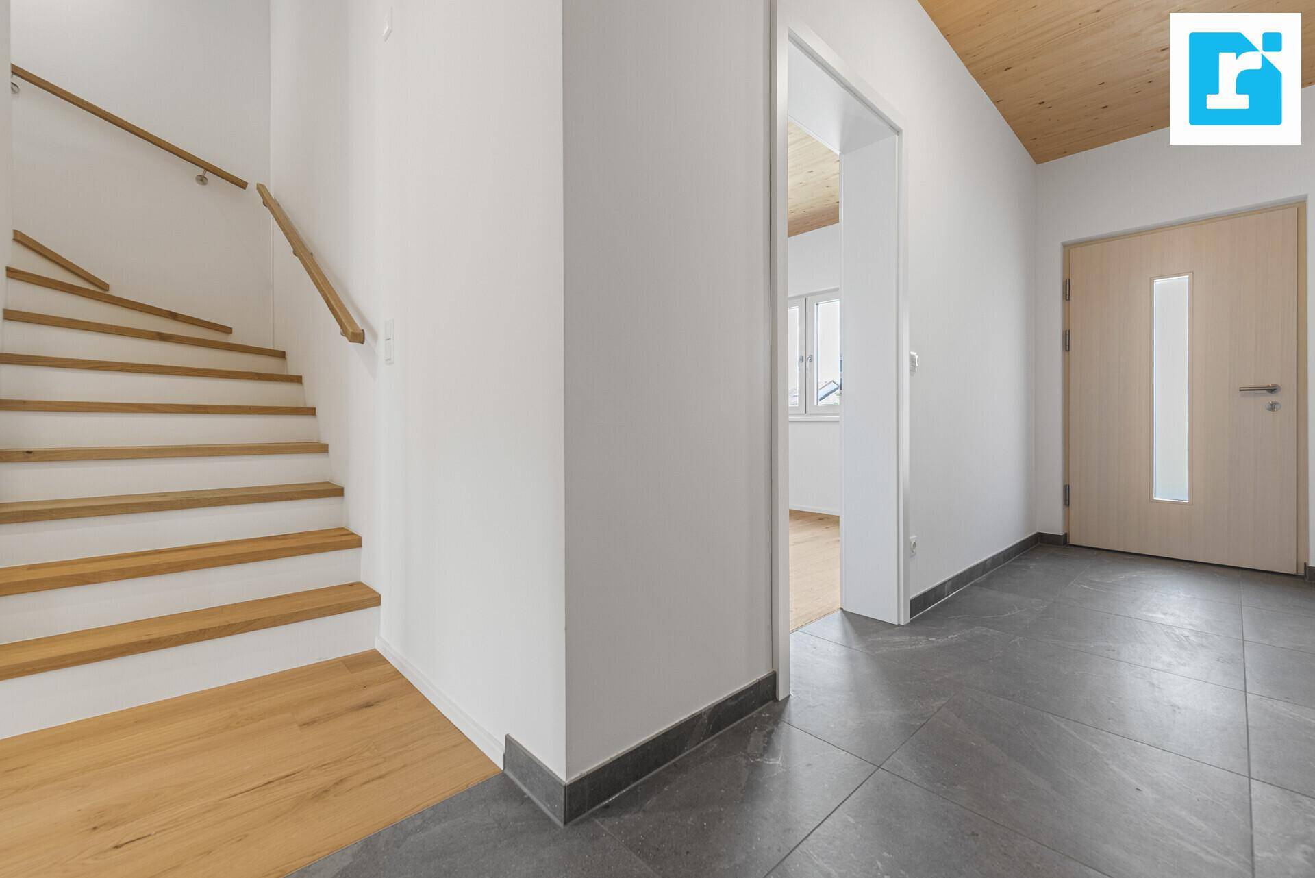 Eingangsbereich mit Holztreppe, Fliesenboden und Zugang zu weiteren Räumen.