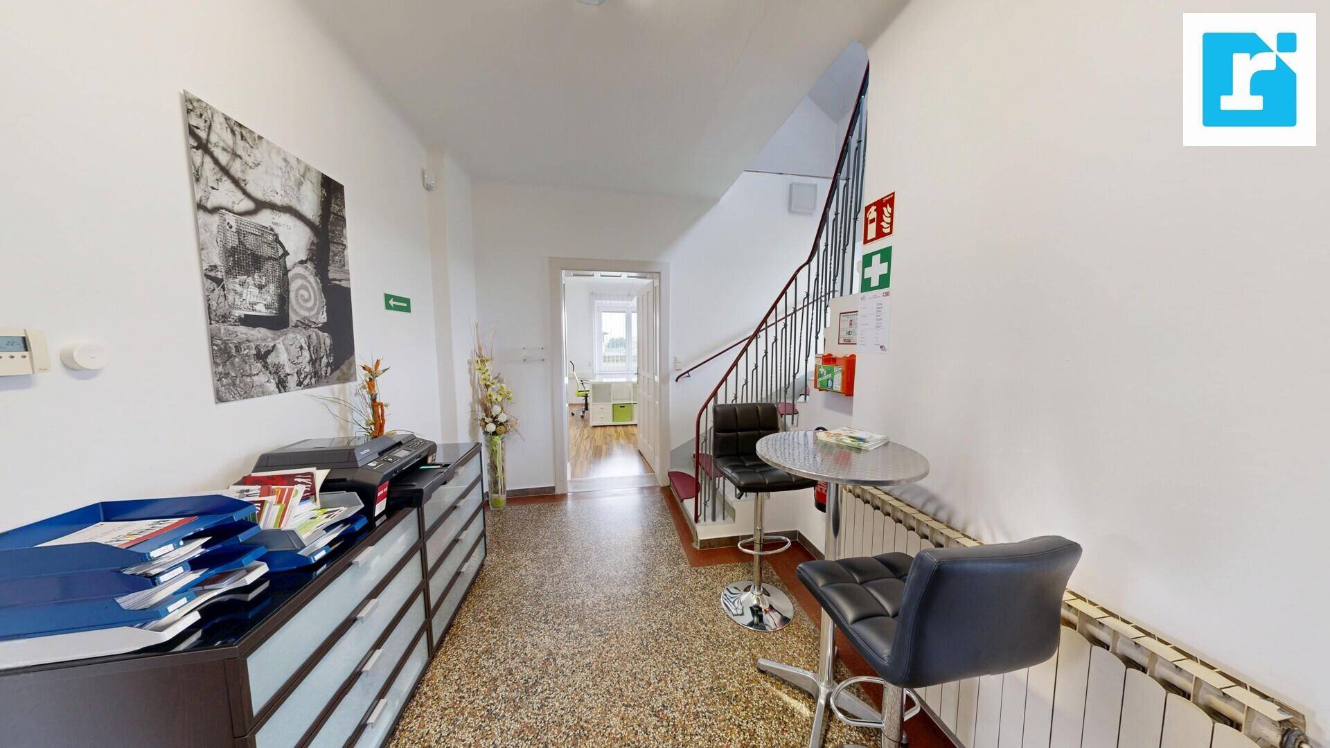 Geräumiger Flur mit Terrazzoboden, einem Aktenschrank und einer geschwungenen Treppe zum Obergeschoss.