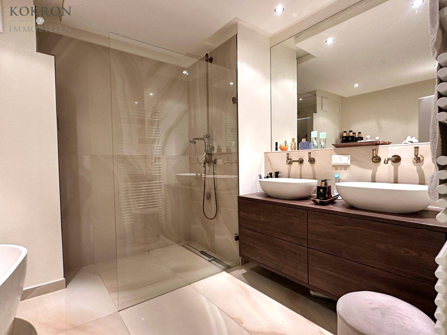 Modernes Badezimmer mit Doppelwaschbecken, großer begehbarer Dusche und beheiztem Handtuchhalter.