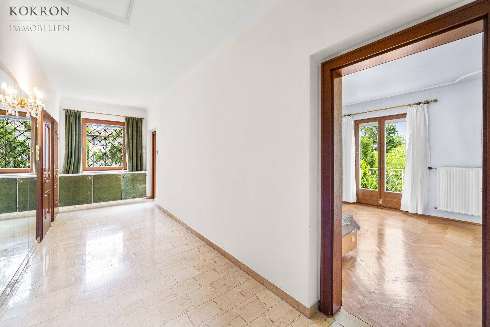 Heller Flur mit Fliesenboden, Spiegelwand und Blick in angrenzende Zimmer.