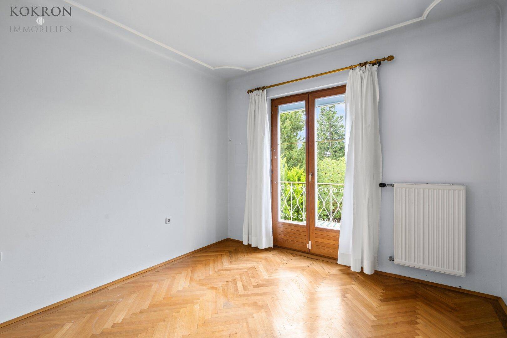 Helles Schlafzimmer mit Fischgrätparkett, hellblauen Wänden und französischem Balkon.