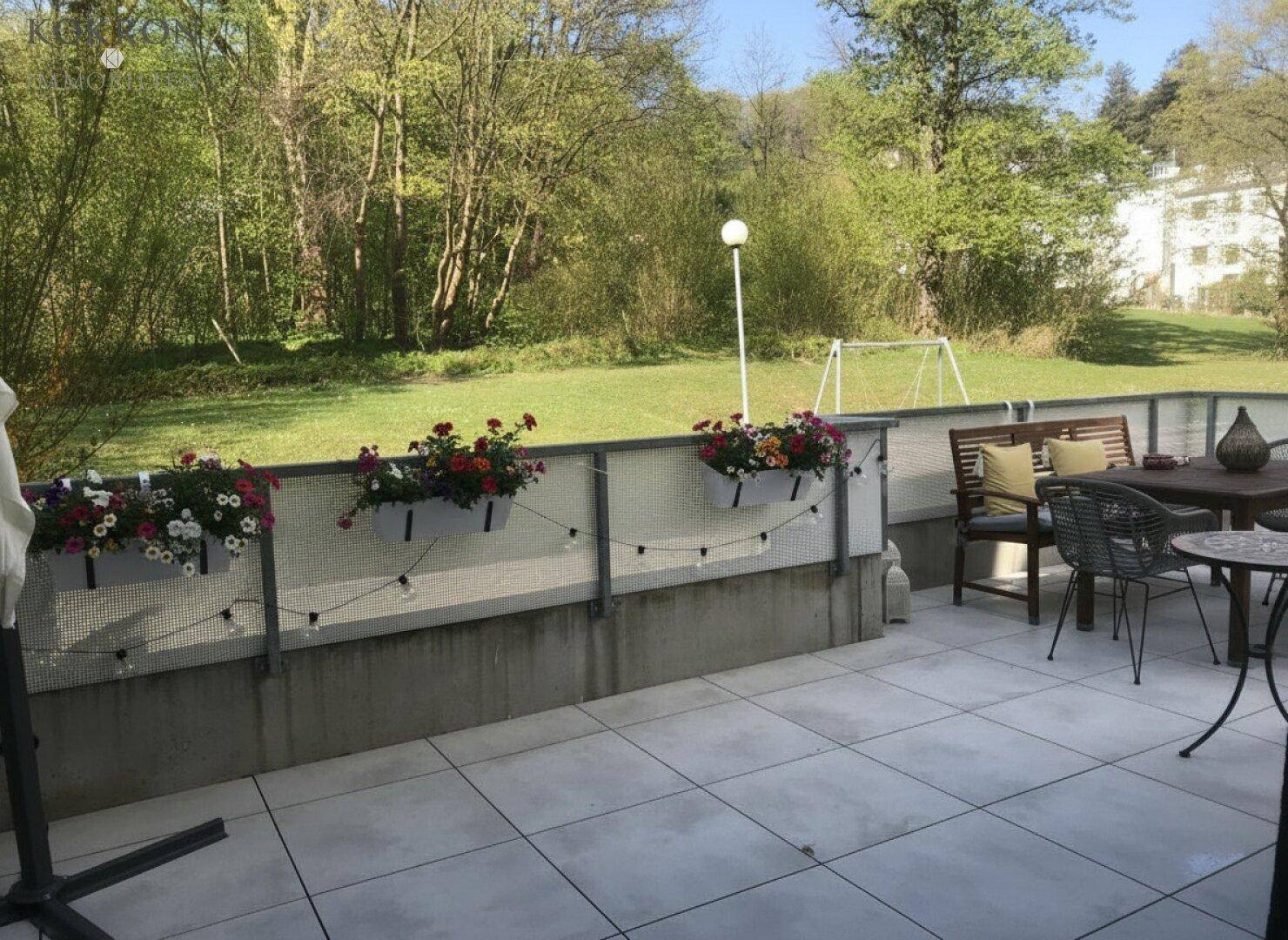 Geräumige Terrasse mit Sitzgelegenheiten und Blick auf den Gemeinschaftsgarten und die grüne Umgebung.