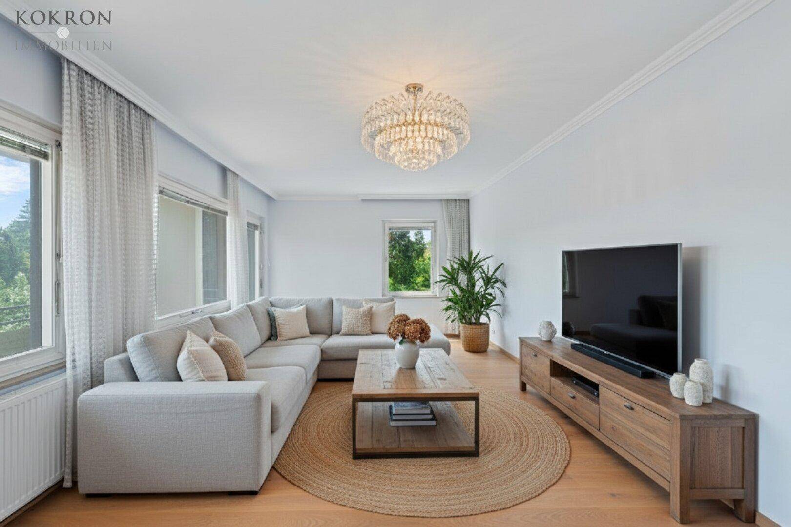 Helles Wohnzimmer mit großem Ecksofa, Holzboden und Blick ins Grüne durch die Fenster.