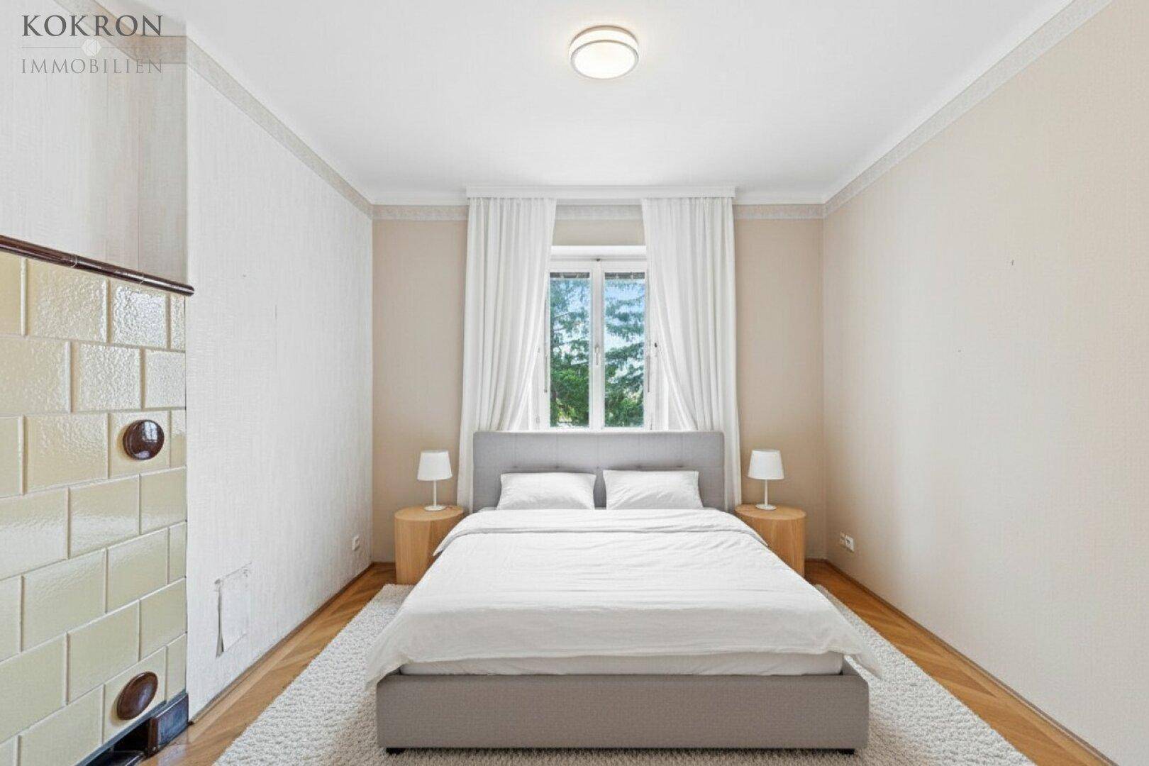 Gemütliches Schlafzimmer mit einem bequemen Doppelbett, Holzboden und einem traditionellen Kachelofen an der Wand.