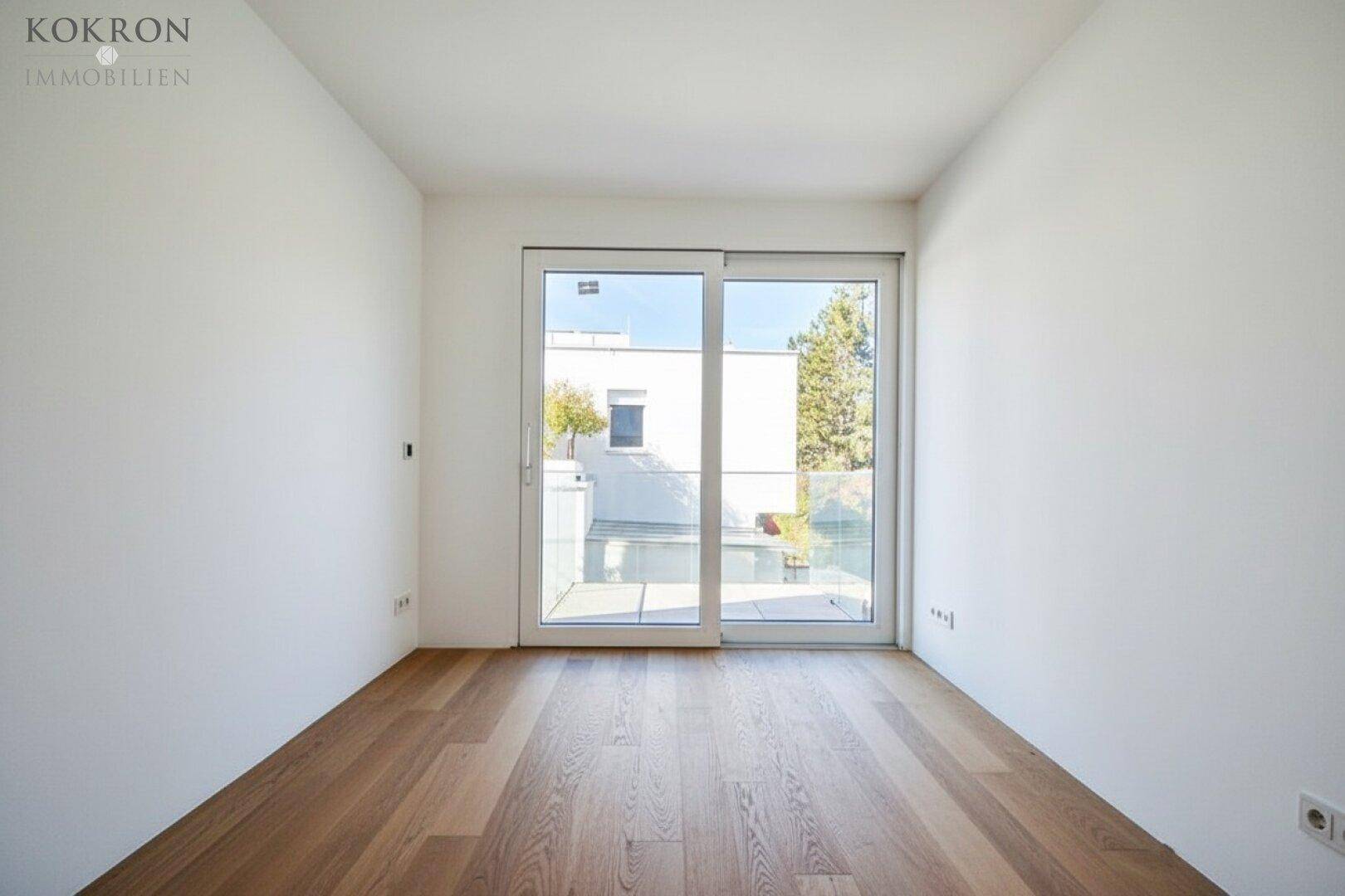 Schlafzimmer mit Holzboden und Schiebetür, die zu einem Außenbereich führt.
