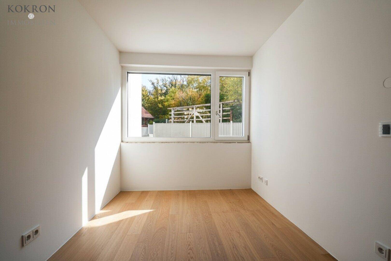 Helles Schlafzimmer mit Holzboden und großem Fenster mit Blick auf die Umgebung.