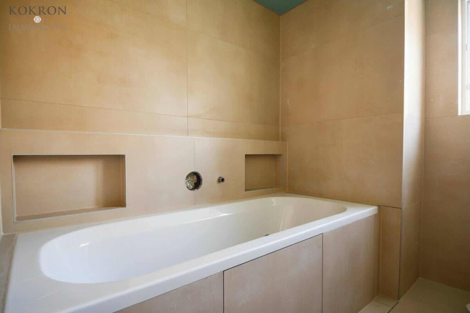 Modernes Badezimmer mit eingebauter Badewanne und beigefarbenen Fliesen.