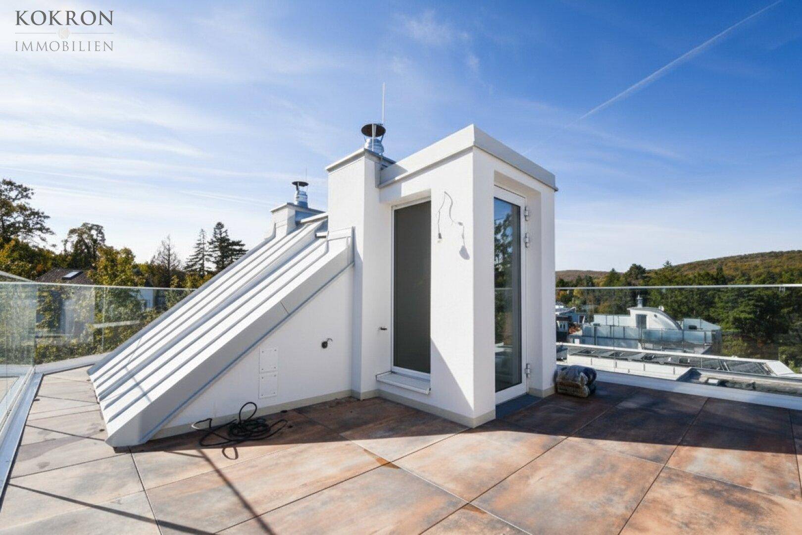 Sonnige Dachterrasse mit Zugang zum Gebäude und weitem Blick über die Umgebung.