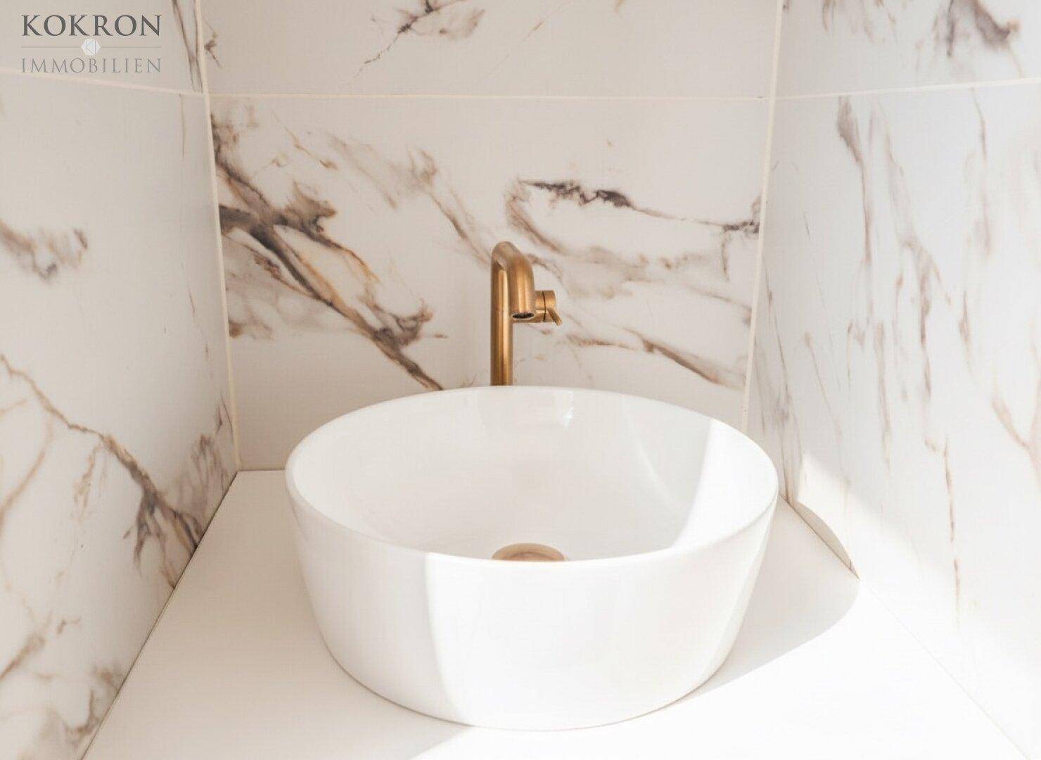 Moderner Waschtisch mit runder Aufsatzschale und goldfarbenem Wasserhahn als stilvolles Detail.