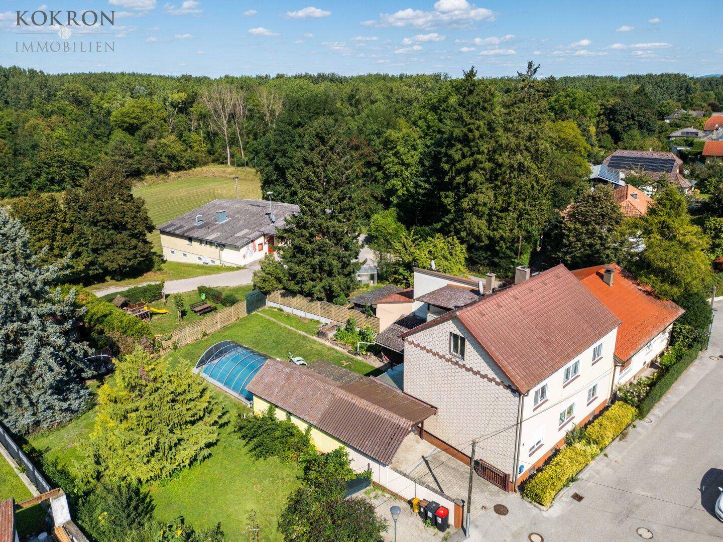 Überblick über das Wohnhaus mit Garten, Pool und angrenzendem Waldgebiet aus der Vogelperspektive.