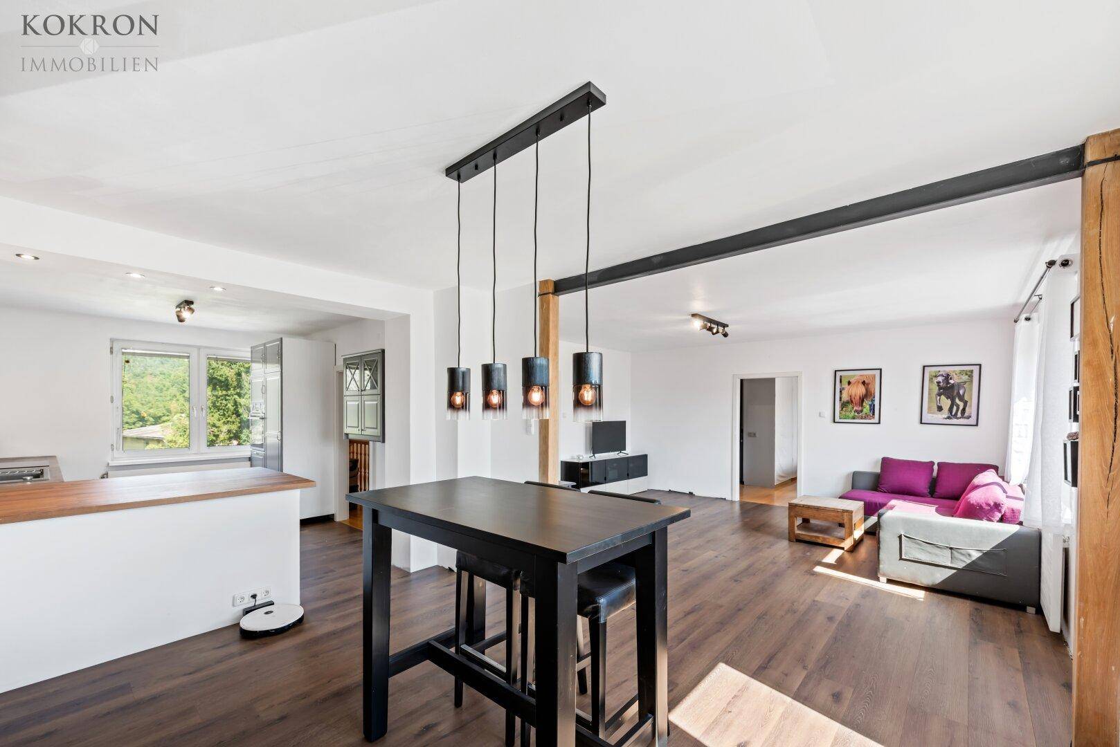 Geräumiger offener Wohnbereich mit Holzboden, Bartisch und gemütlicher Sitzecke, verbunden mit der Küche.