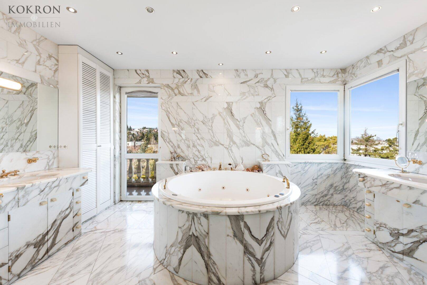 Luxuriöses Badezimmer komplett in Marmor gehalten, mit einem runden Whirlpool und Balkonzugang.