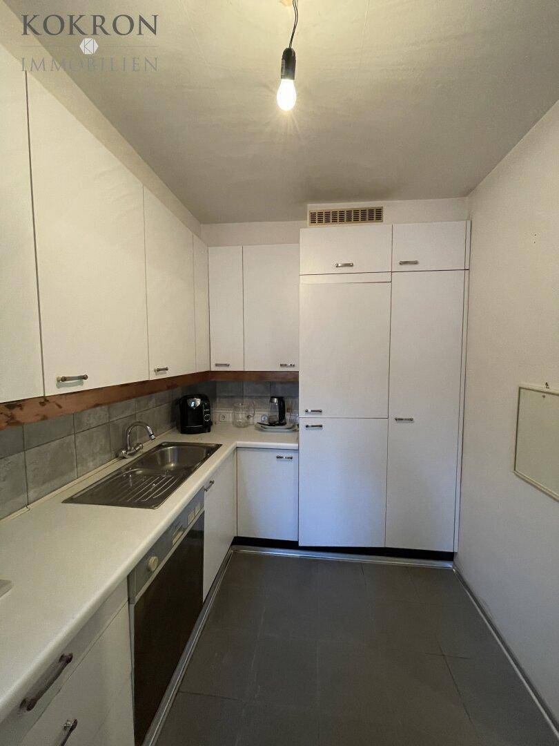Funktionale Küche mit weißen Schränken, Fliesenrückwand und Spülbecken.