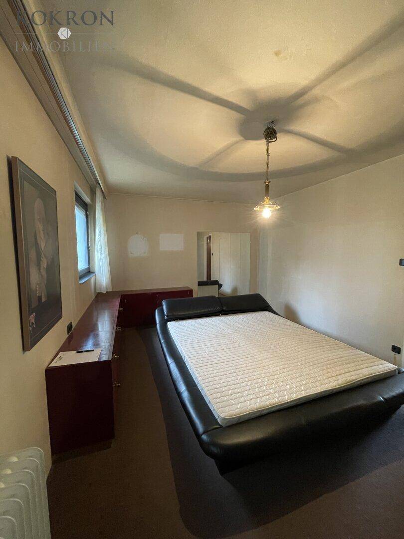Geräumiges Schlafzimmer mit Doppelbett, Kommode und Fenster.