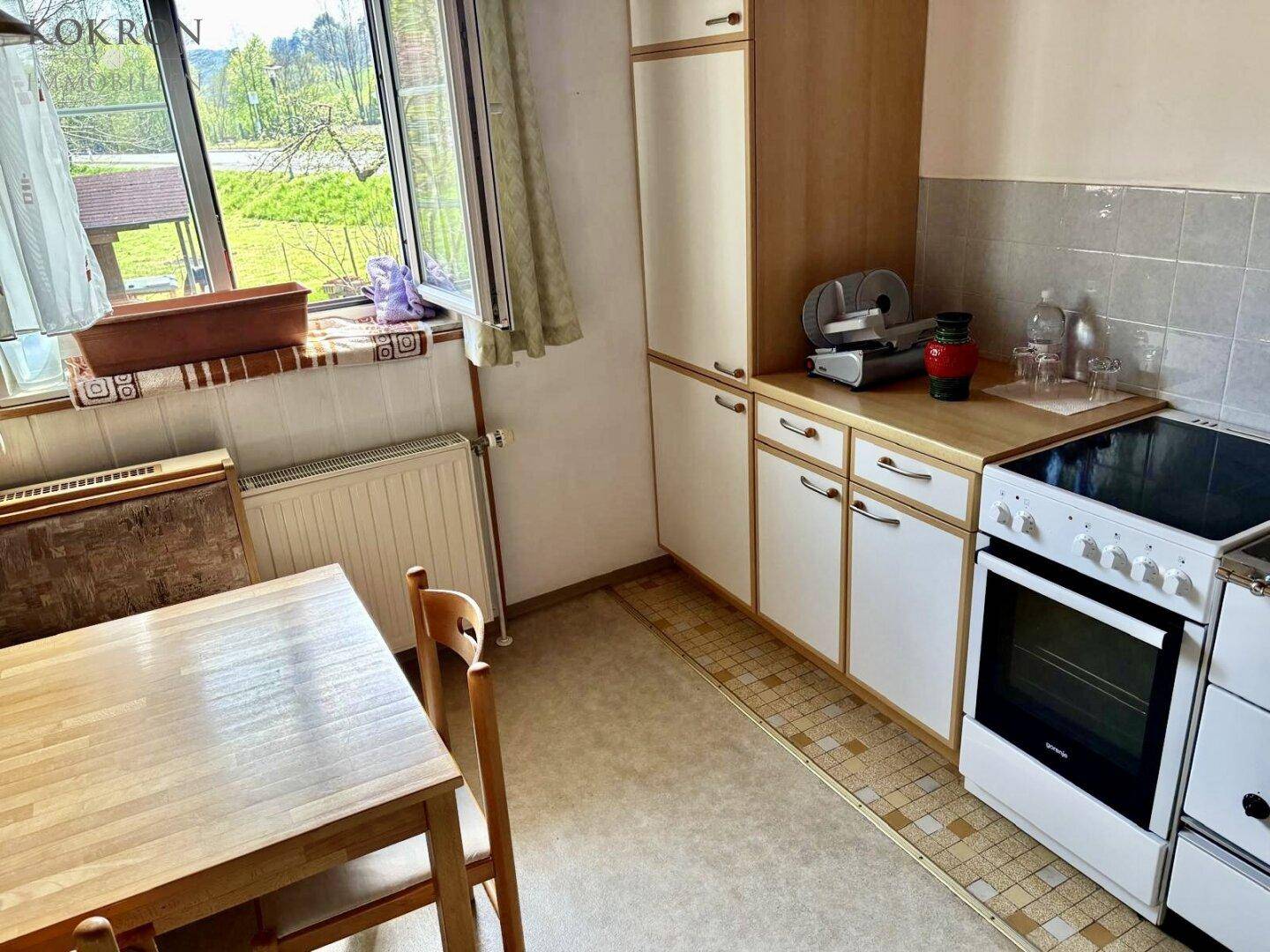 Einfache Küche mit Esstisch, Herd und Fenster mit weitem Blick in die Landschaft.