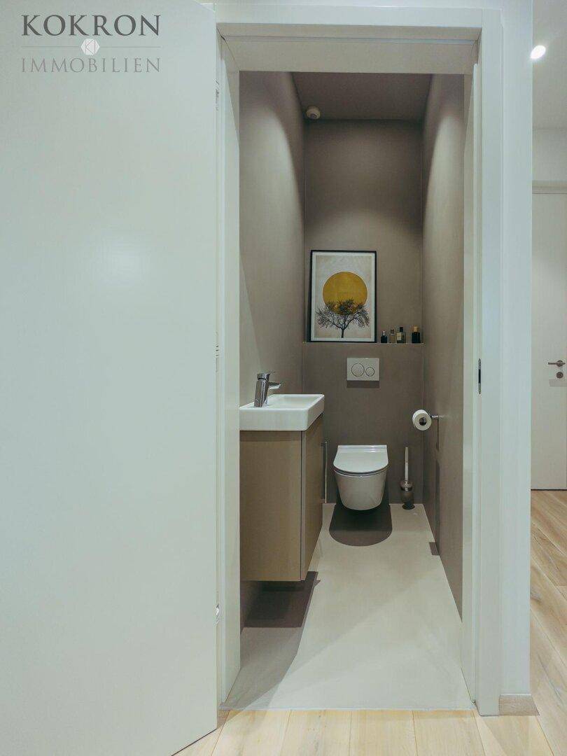 Kleines Gäste-WC mit wandhängender Toilette und modernem Waschbecken.