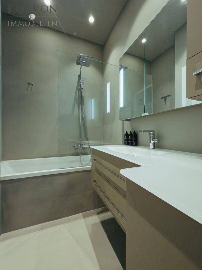 Modernes Badezimmer mit Badewanne, Duschabtrennung und großem Waschtisch.