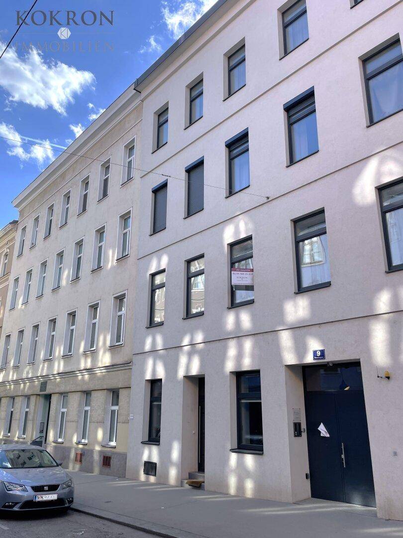 Historisches Gebäude mit mehreren Etagen und klassischen Fenstern an einer Straße.