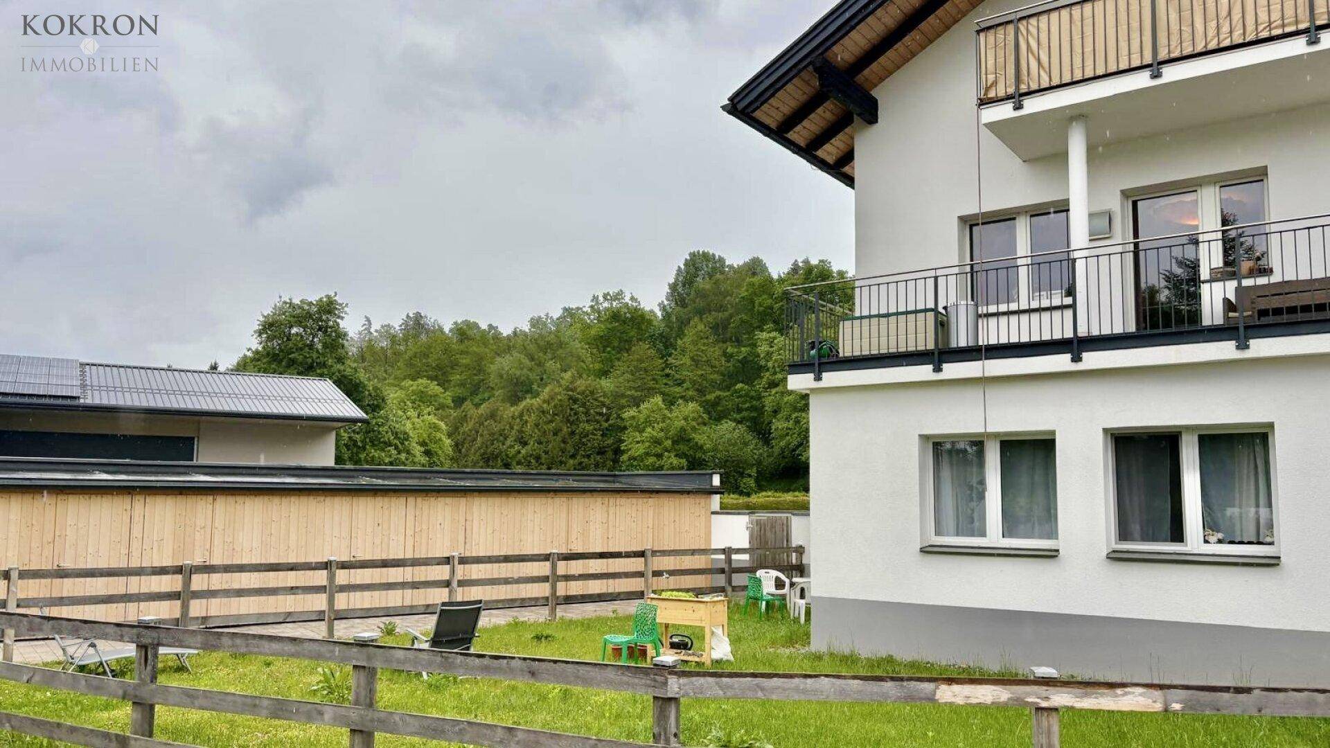 Seitenansicht des Hauses mit Balkon und Blick auf den Gartenbereich und angrenzende Gebäude.